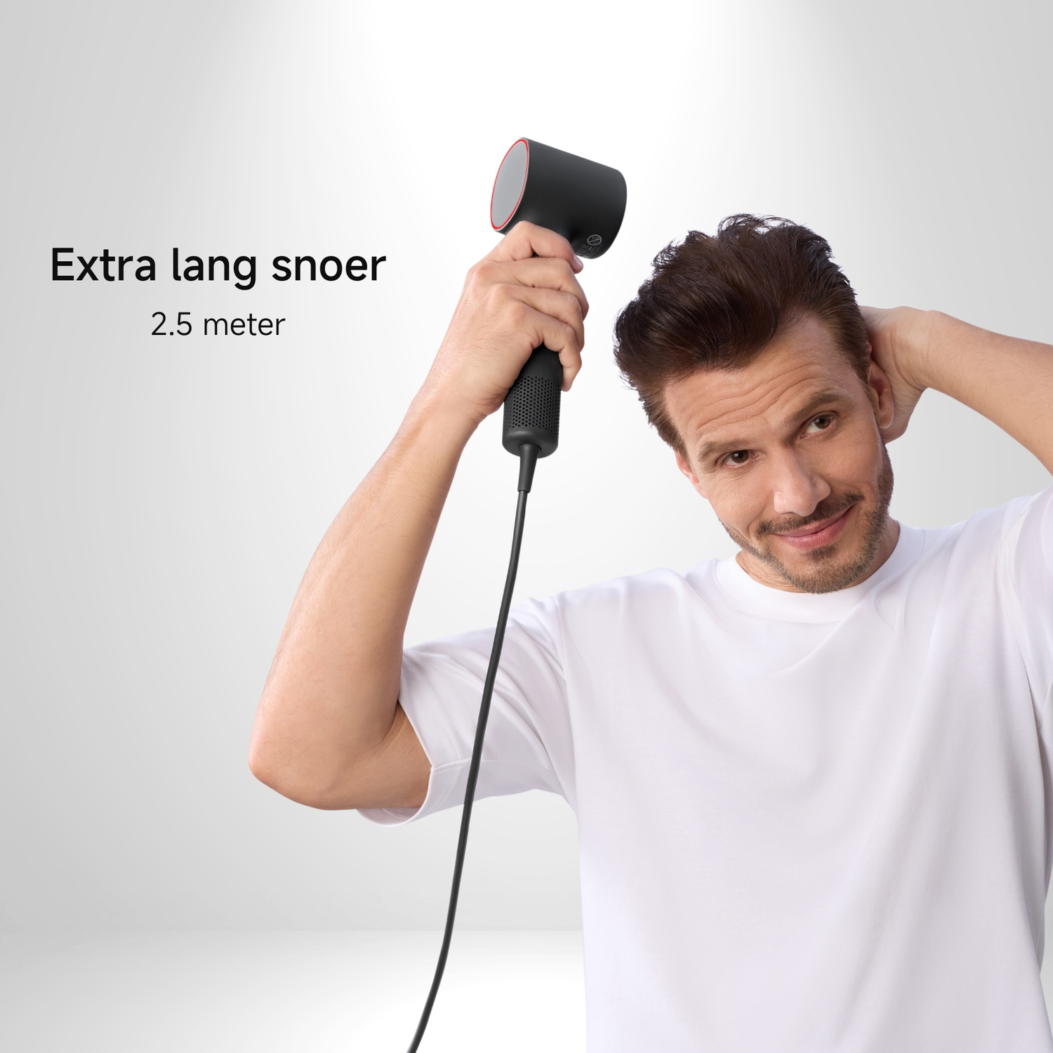 A man holding a black hairdryer, smiling, with a white t-shirt. Text: Extra long cord, 2.5 meters.