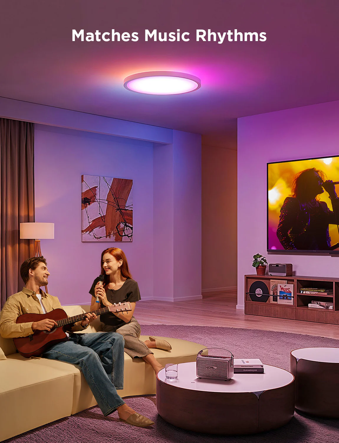Una coppia canta e suona la chitarra in un soggiorno. C'è una luce che cambia colore sopra. Un televisore riproduce musica.