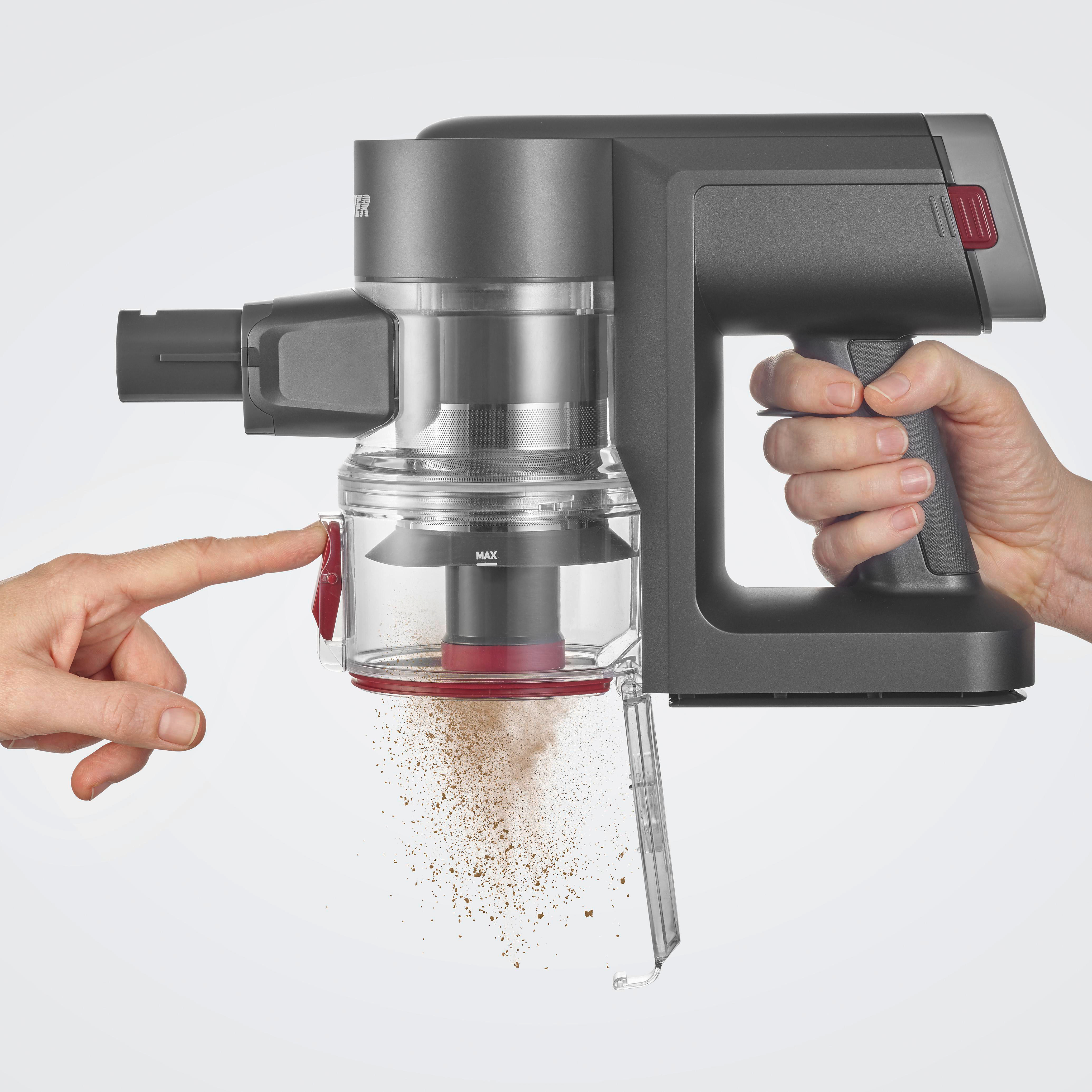 Ein grauer Handstaubsauger wird mit zwei Händen gehalten. Ein Finger drückt einen roten Knopf und setzt Staub frei.