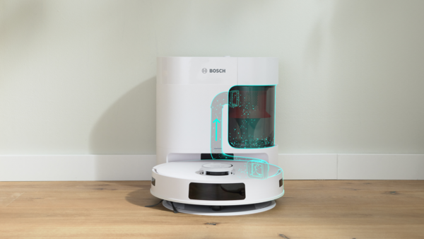 Beyaz bir Bosch robot süpürgesi ve şarj istasyonu. Süpürge ahşap bir zeminde, arka plan ise bir duvar.