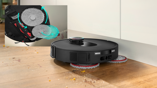 Dönen pedlere sahip siyah bir robot süpürge, ahşap bir zemini temizliyor. Bir ek, pedlerin temizleme eylemini, döküntülerle birlikte gösteriyor.