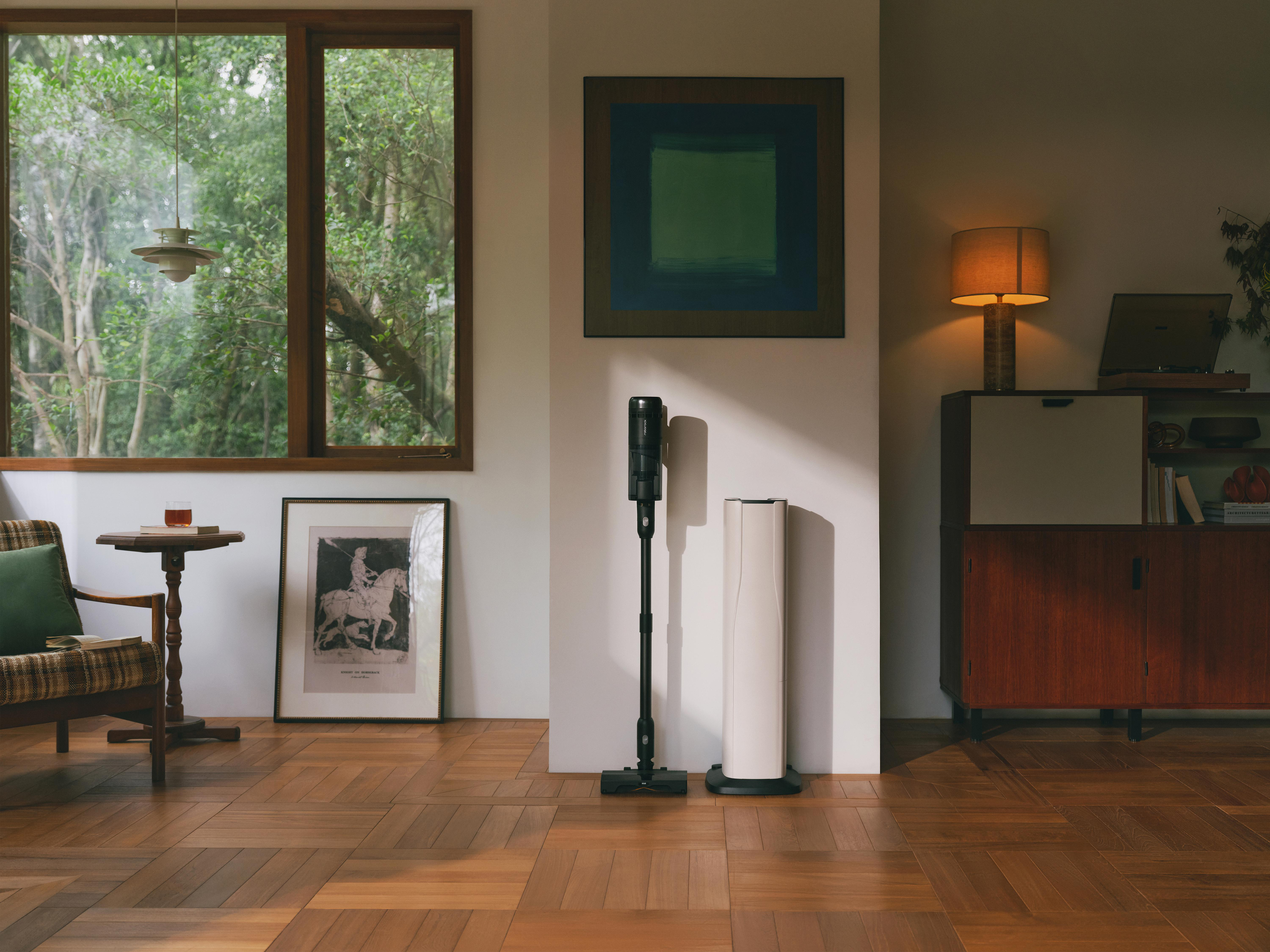 Ein modernes Wohnzimmer mit Staubsauger, Kunst, Fenster und Holzboden.