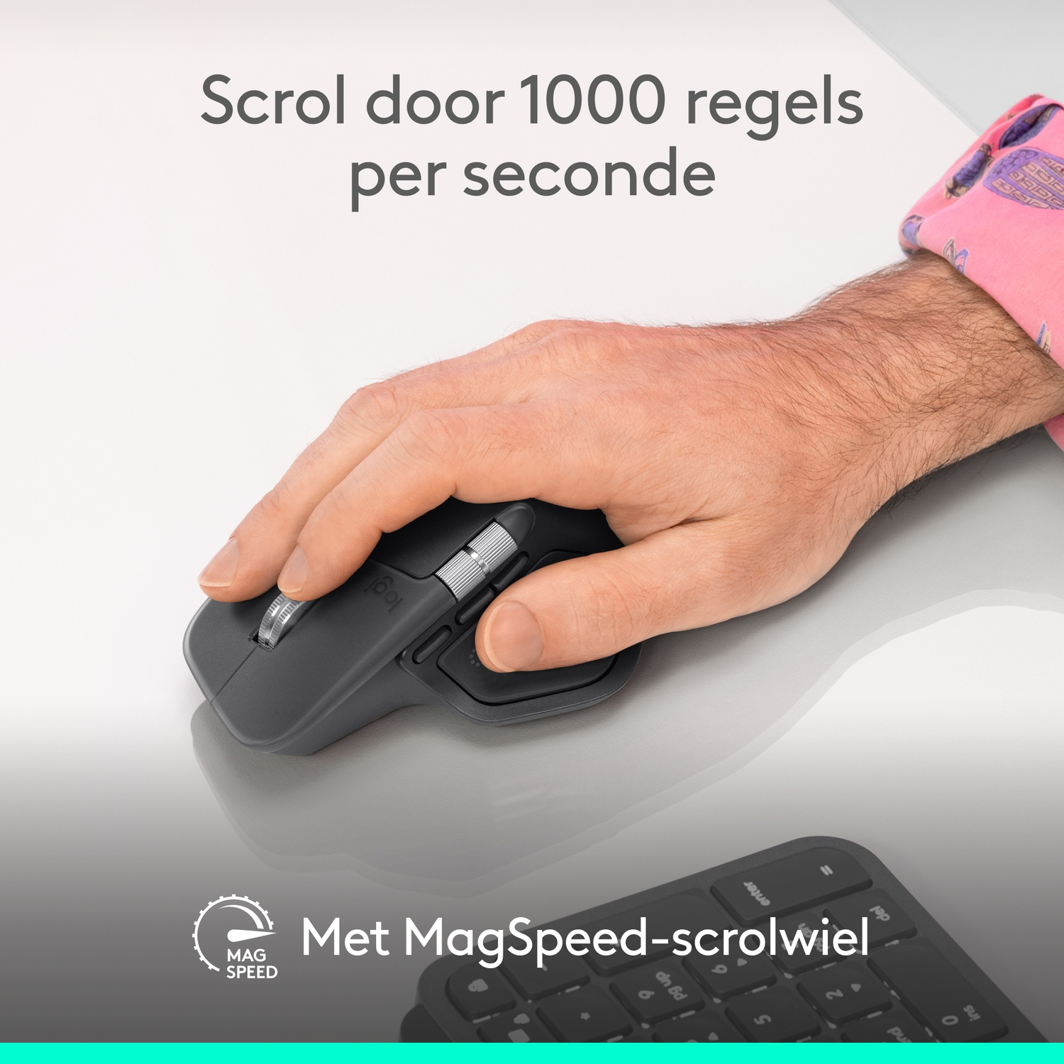 A hand holds a gray Logitech mouse on a desk. A keyboard is in the foreground. Text says 'MagSpeed-scrolwiel'.