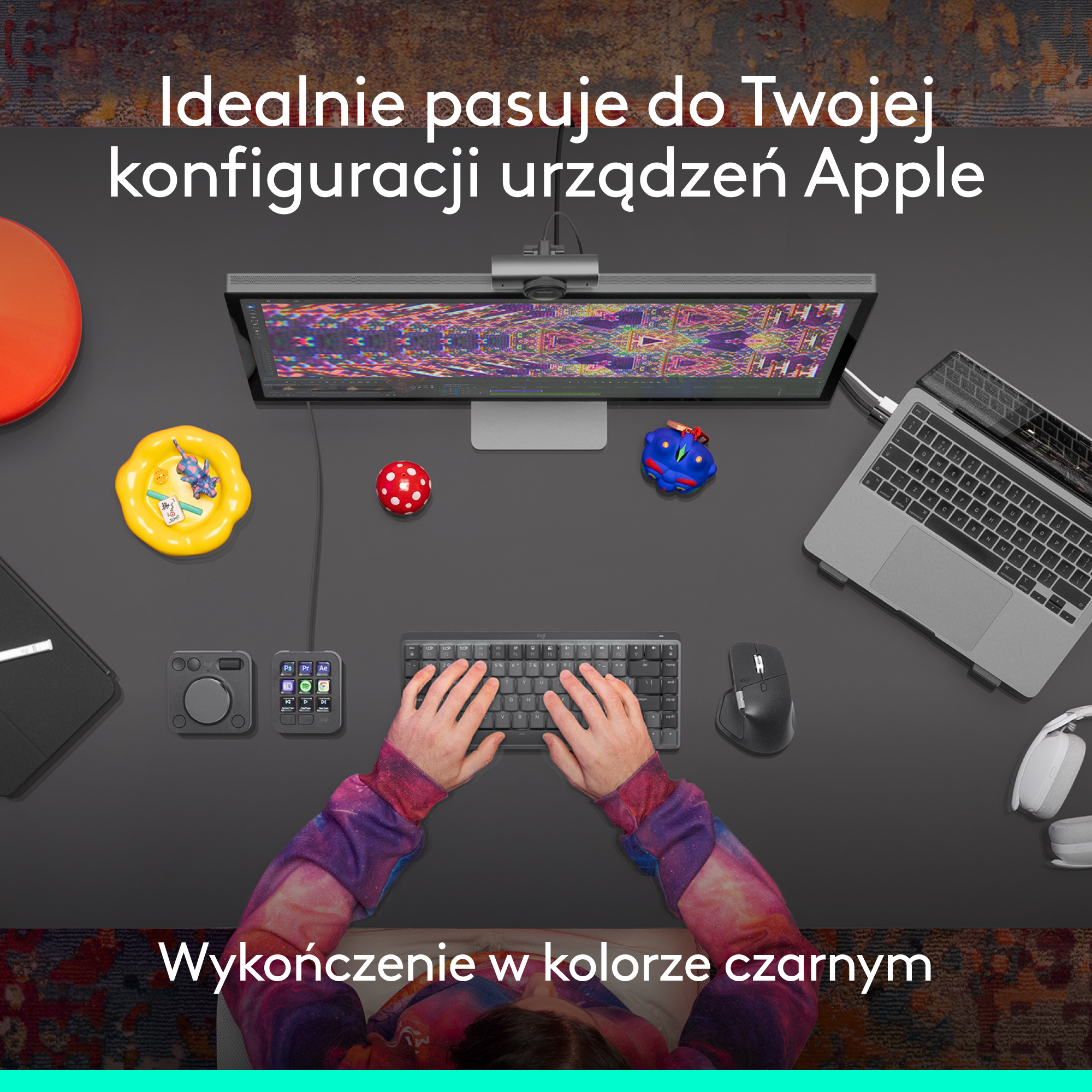 Konfiguracja biurka z monitorem, klawiaturą, myszą, laptopem i akcesoriami. Ręce na klawiaturze. Reklamowane jest czarne wykończenie.