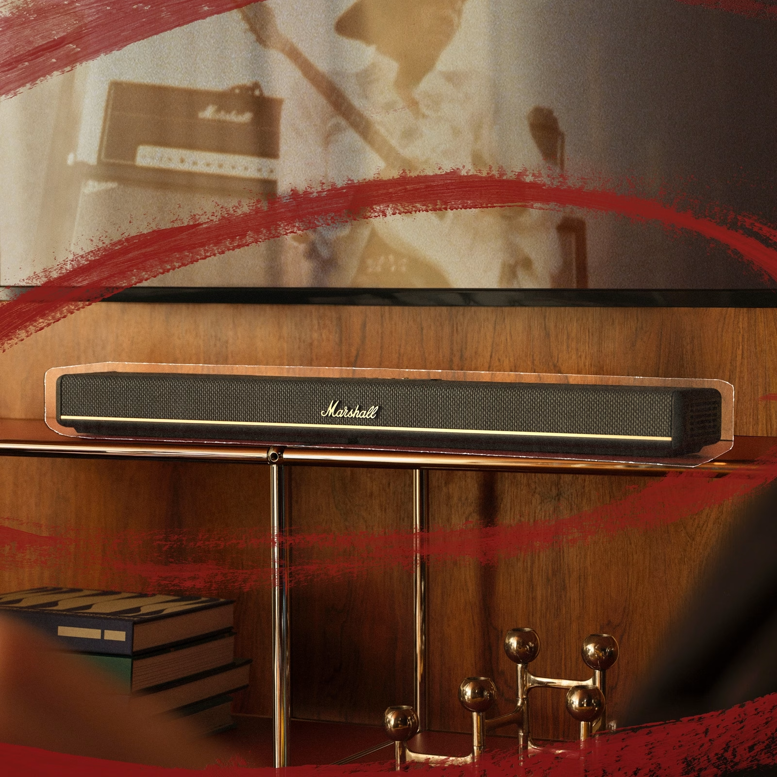 Eine Marshall-Soundbar steht auf einem Regal. Bücher und Kerzenhalter befinden sich auf dem Regal darunter. Rote Pinselstriche rahmen die Szene ein.
