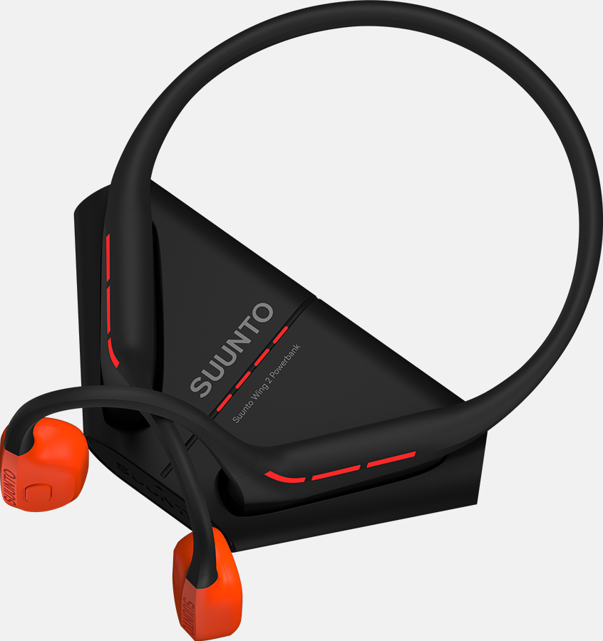 Schwarzes Suunto Wing 2 Powerbank mit orangefarbenen Ohrhörern. Das Headset hat ein Nackenband und ruht auf einer schwarzen Ladestation.