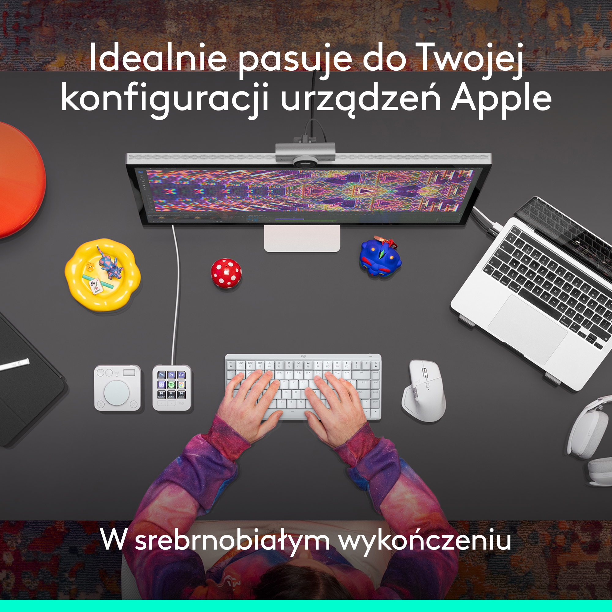 Biurko z monitorem, klawiaturą, myszką i akcesoriami. Dłonie piszą. Tekst: 'Idealnie pasuje do konfiguracji urządzeń Apple'.