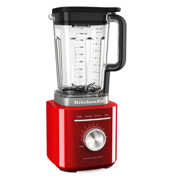Egy piros KitchenAid turmixgép. Átlátszó edénye van, fekete fedéllel és sebességszabályzó gombbal.