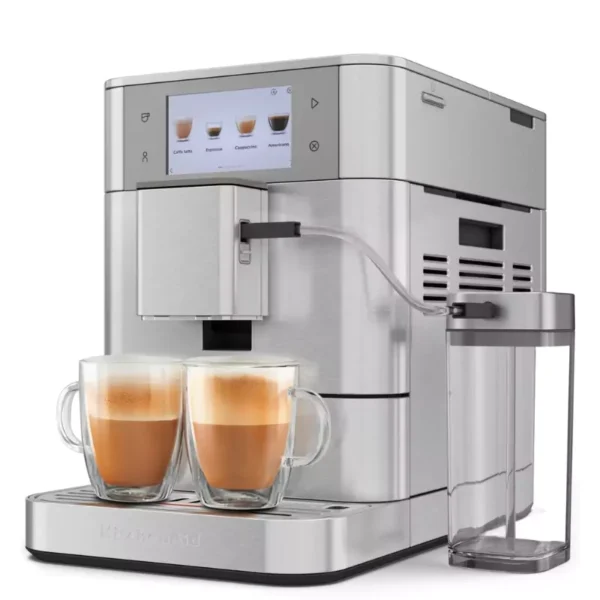 Ezüst KitchenAid eszpresszó gép két kávéscsészével. Az érintőképernyő kávé opciókat mutat. A jobb oldalon egy víztartály található.