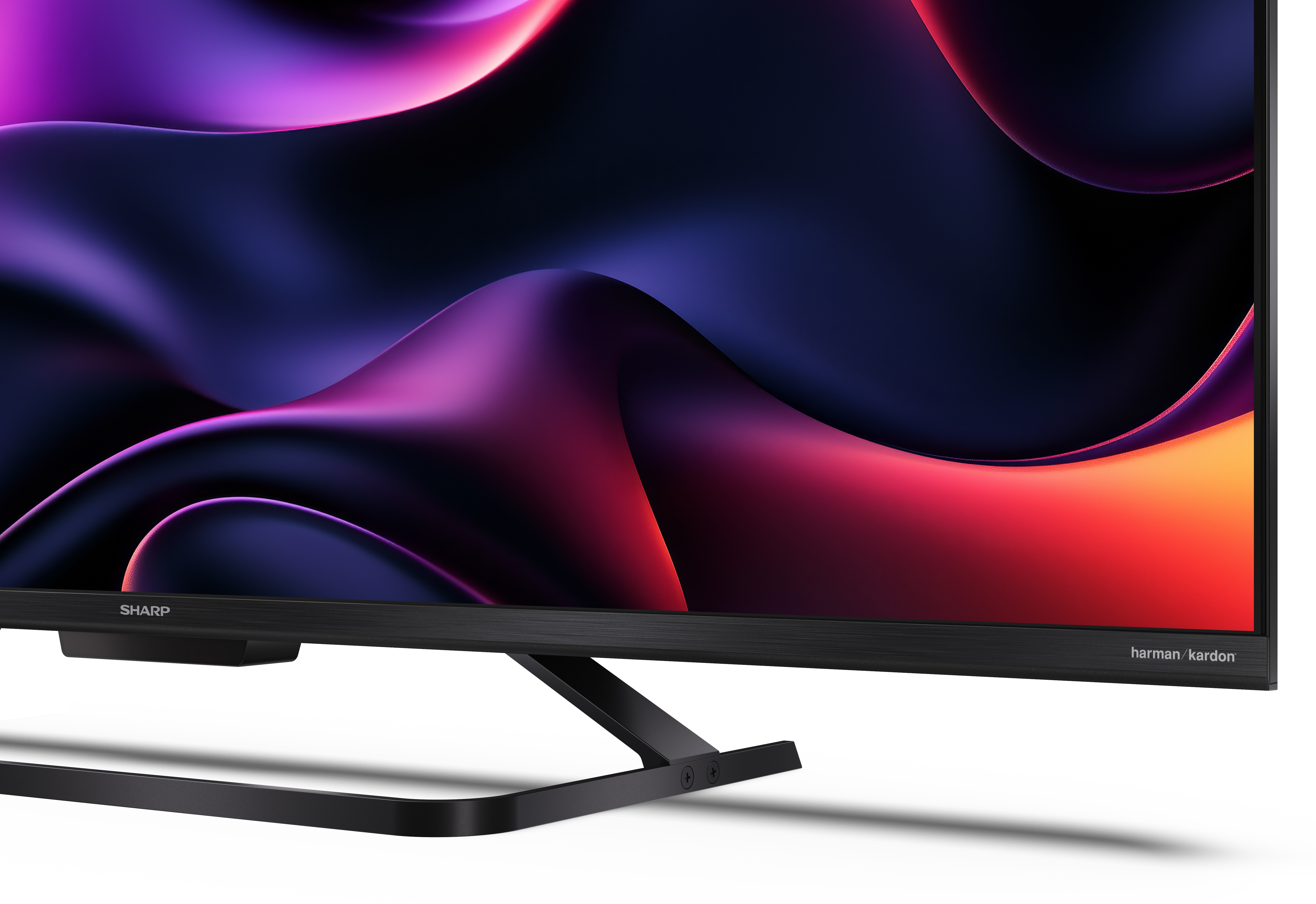 Telewizor Sharp z czarną ramą. Ekran wyświetla abstrakcyjne, faliste kształty w odcieniach fioletu i czerwieni.