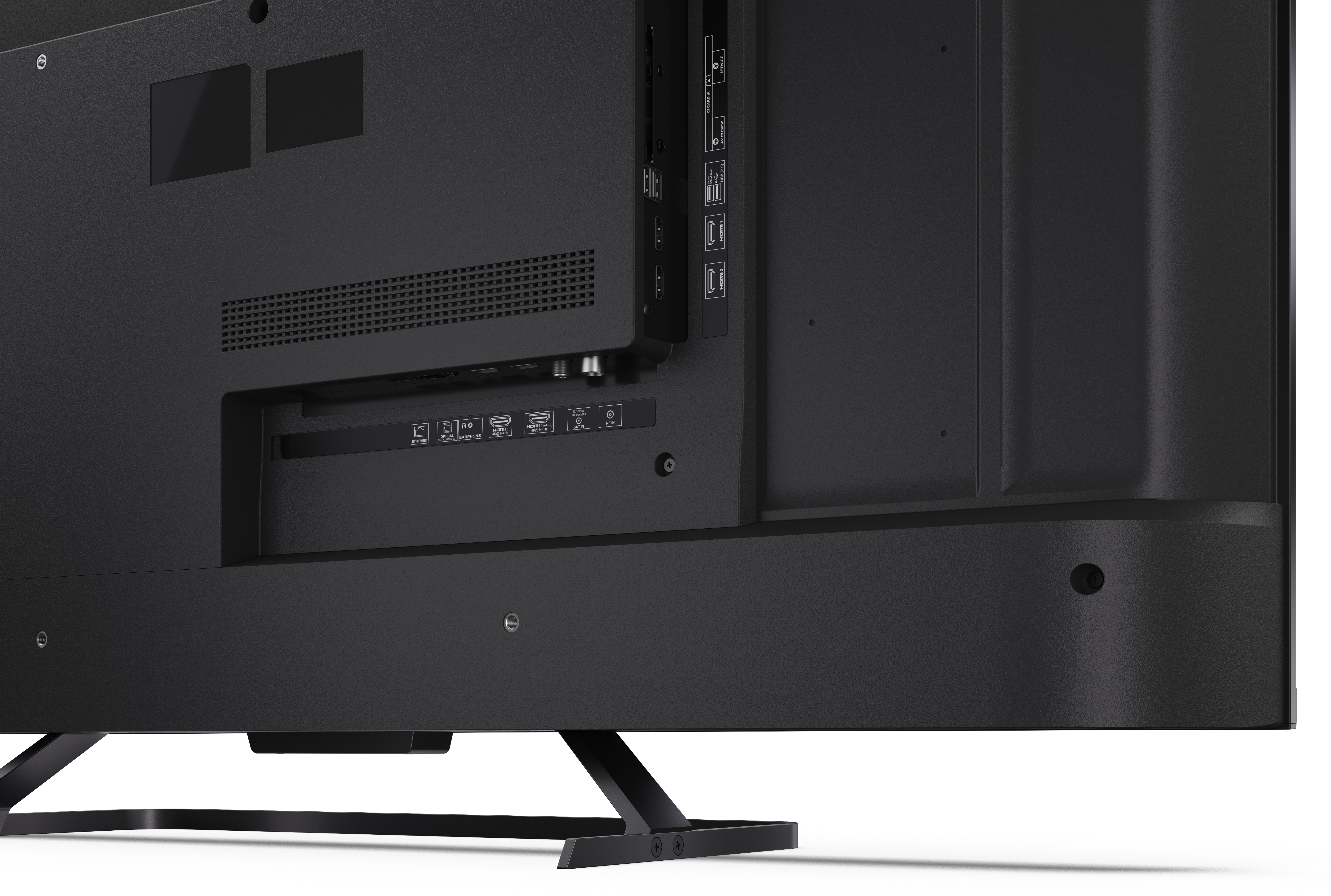 Widok z tyłu czarnego telewizora. Posiada różne porty, takie jak HDMI, USB i audio. Telewizor stoi na czarnym stojaku.