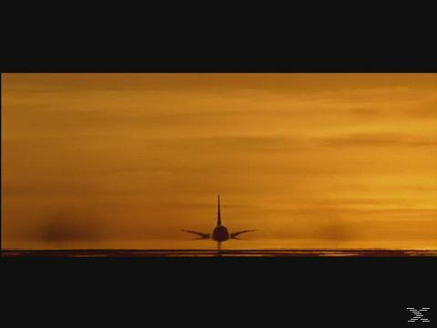 Silhouette eines Flugzeugs am Boden. Der Himmel ist warm orange, was auf Sonnenaufgang oder Sonnenuntergang hindeutet.