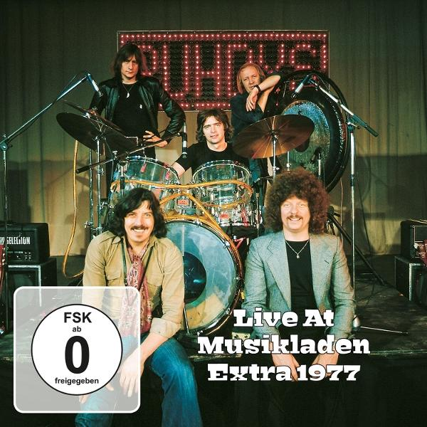 Eine Band aus fünf Männern posiert mit Schlagzeug und Instrumenten. Der Titel 'Live At Musikladen Extra 1977' ist sichtbar. Ein Rating-Aufkleber ist links.