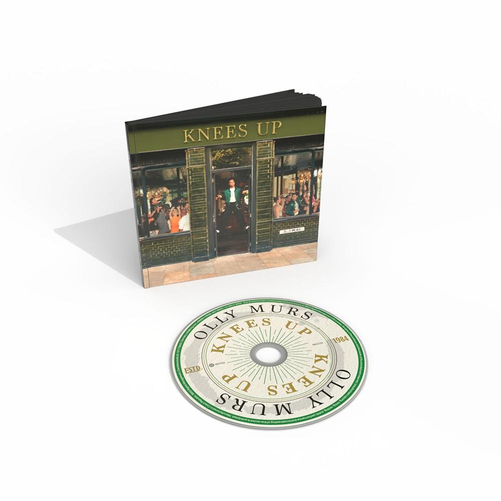 CD und Broschüre mit dem Titel 'Knees Up'. Die Broschüre zeigt einen Mann in einer Tür. CD zeigt 'Olly Murs Knees Up' Text.