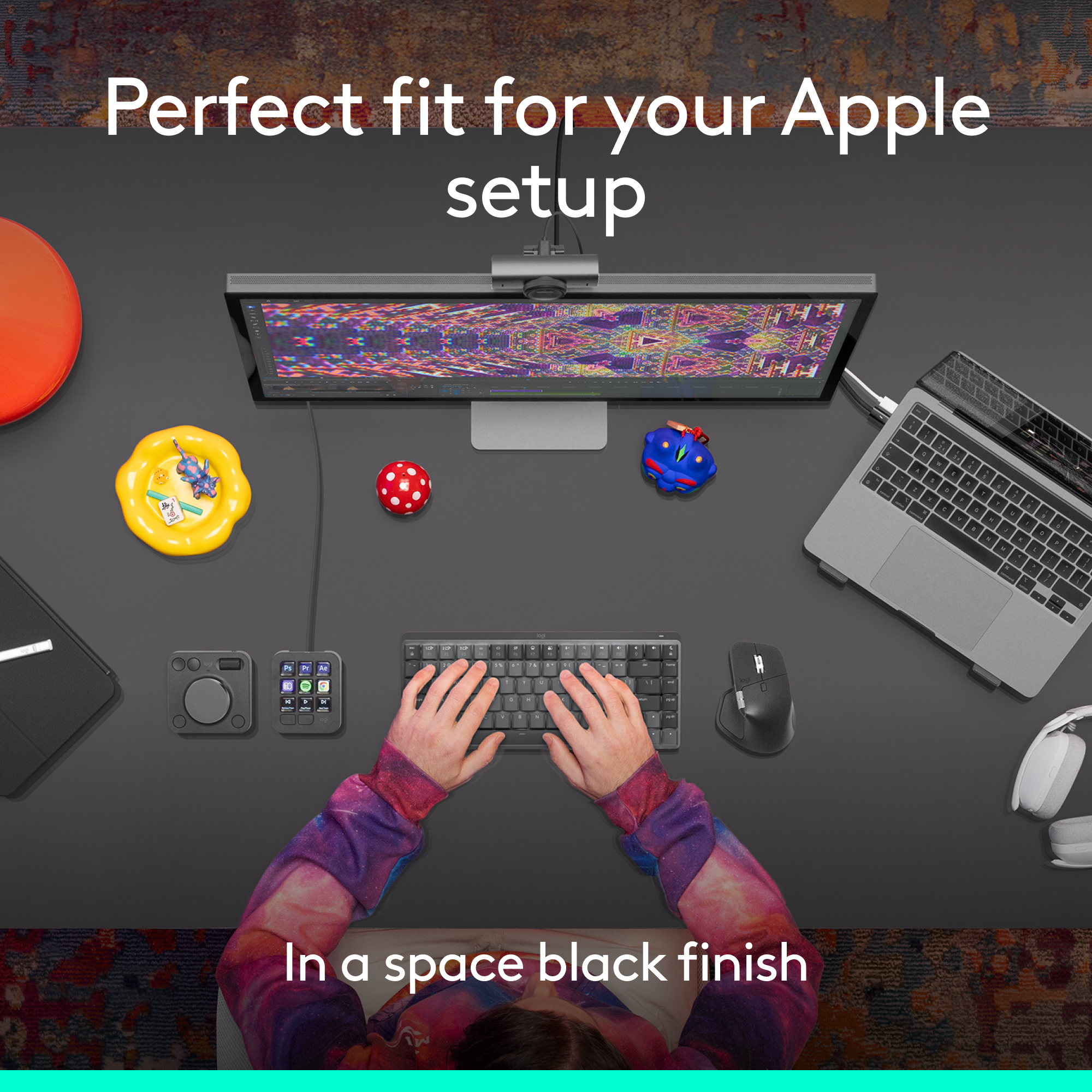 Vue de dessus d'un bureau avec configuration Apple, clavier, souris, moniteur et accessoires. Mains tapant sur le clavier.
