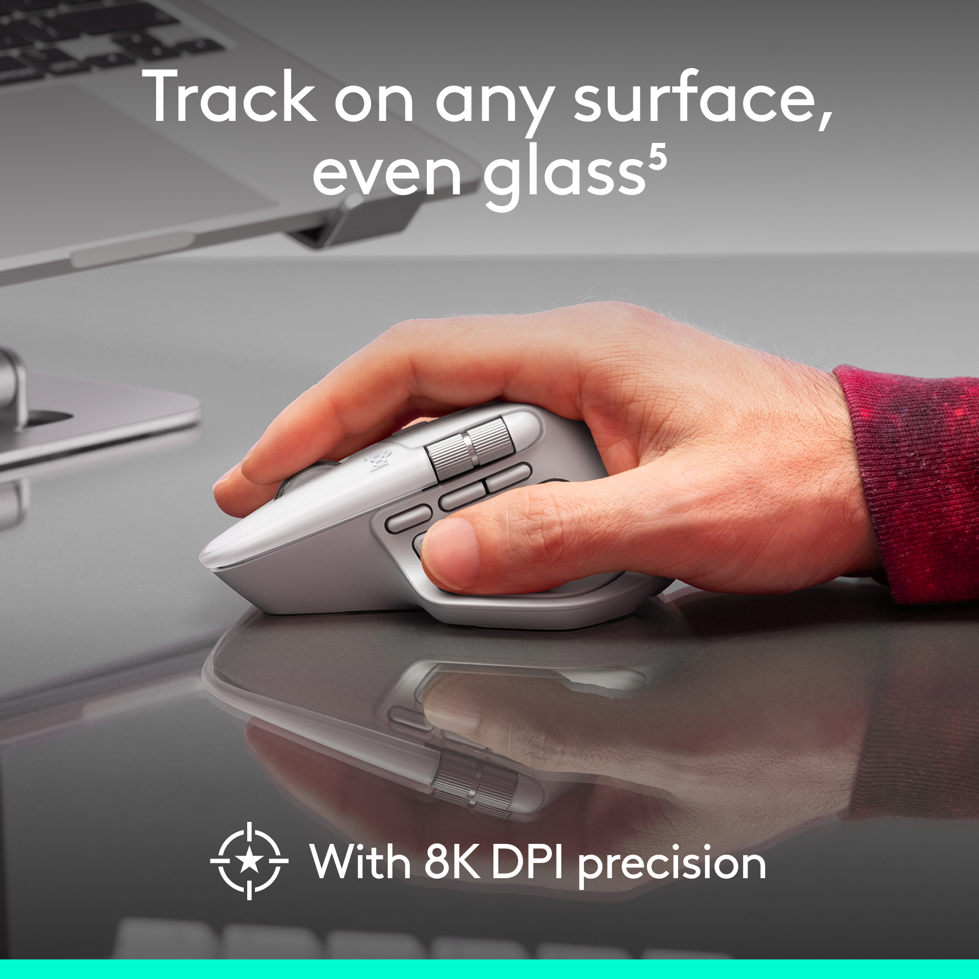 Une main tient une souris grise sur une surface réfléchissante. Texte : Suivez sur n'importe quelle surface, même le verre. Avec une précision 8K DPI.