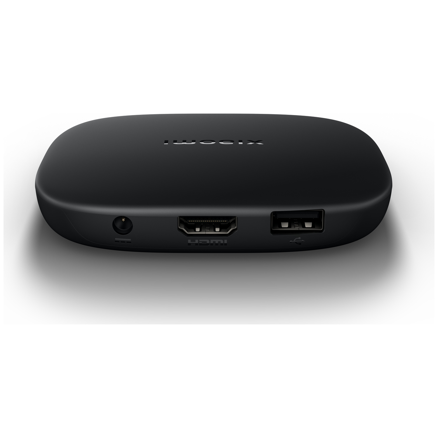 A black, rounded device with ports: audio, HDMI, and USB. The top has a logo. It sits on a white surface, casting a shadow.