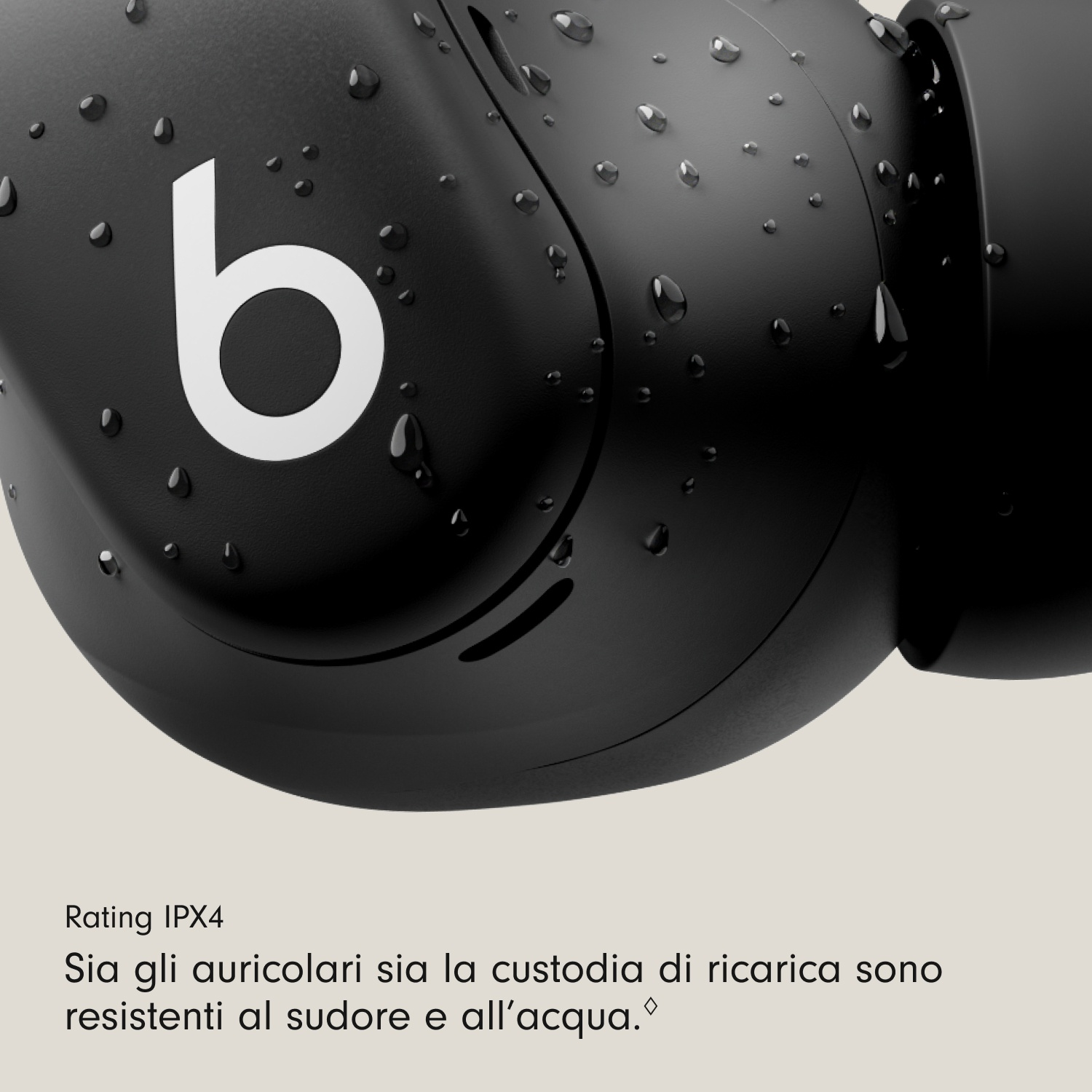 Primo piano di un auricolare nero con logo 'b' bianco, goccioline d'acqua sopra. Lo sfondo è sfocato e beige chiaro.