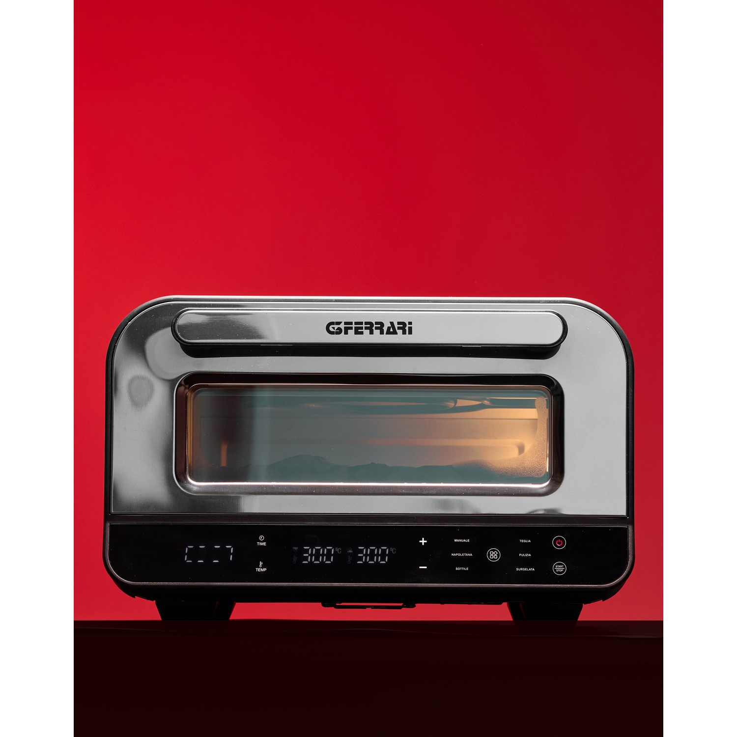 Un forno in acciaio inossidabile con display digitale, che mostra temperatura e tempo, su una superficie scura contro uno sfondo rosso.