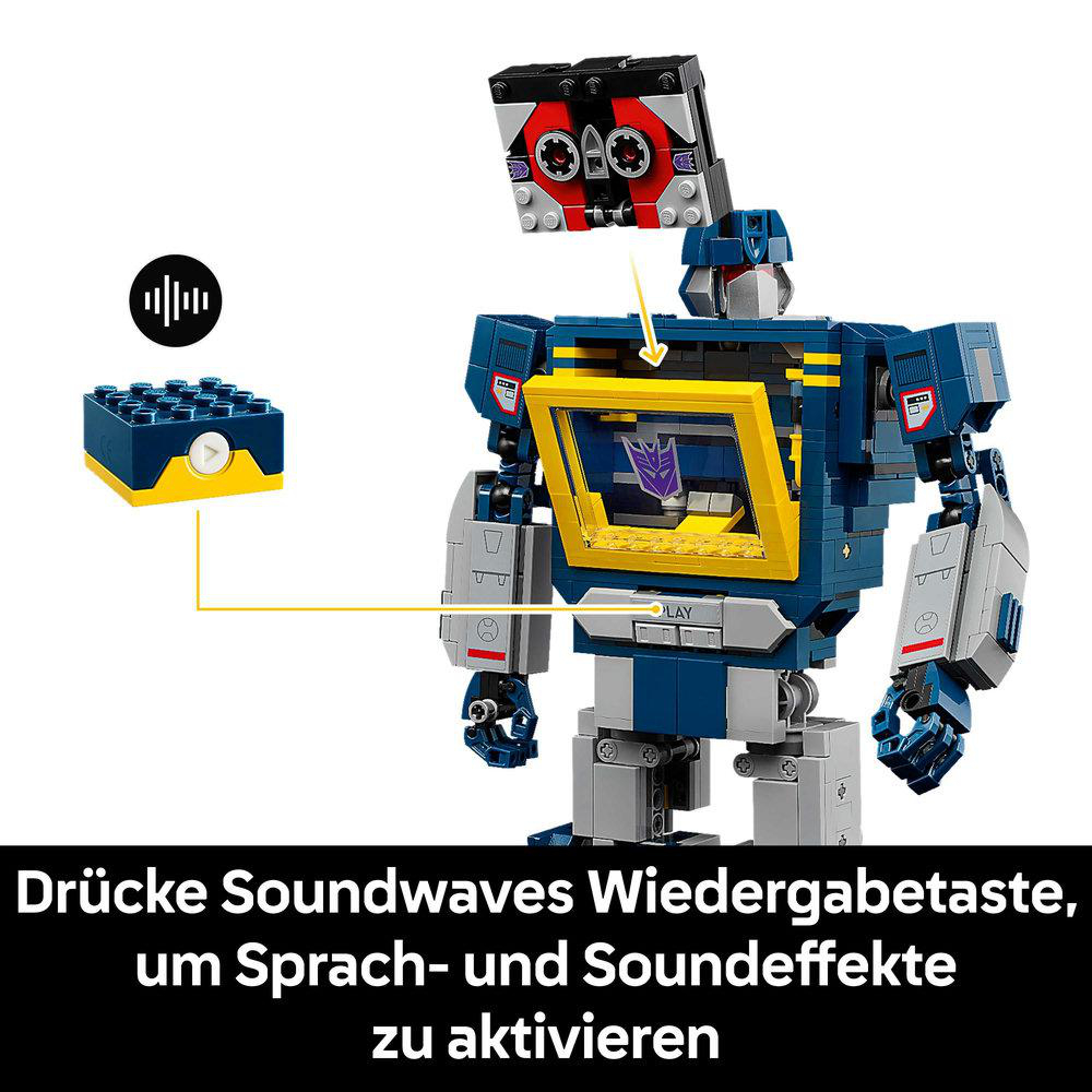 Eine Lego Soundwave-Figur. Sie ist dunkelblau und grau. Der Text besagt, dass man die Wiedergabetaste von Soundwave drücken muss.