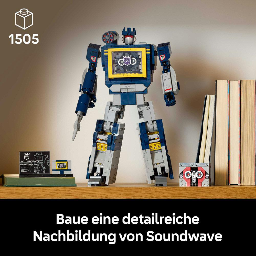 Ein Lego Soundwave-Modell steht auf einem Regal mit einer Kassette, Büchern und einem kleinen Soundwave-Bild.
