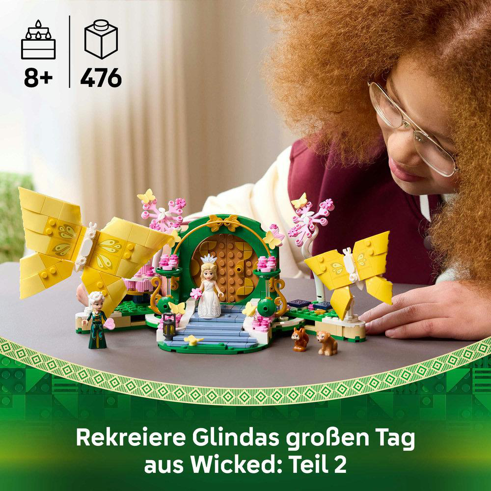Lego-Set mit einem grünen Bogen, gelben Schmetterlingen und Figuren. Darüber eine Person mit Brille und roten Haaren.