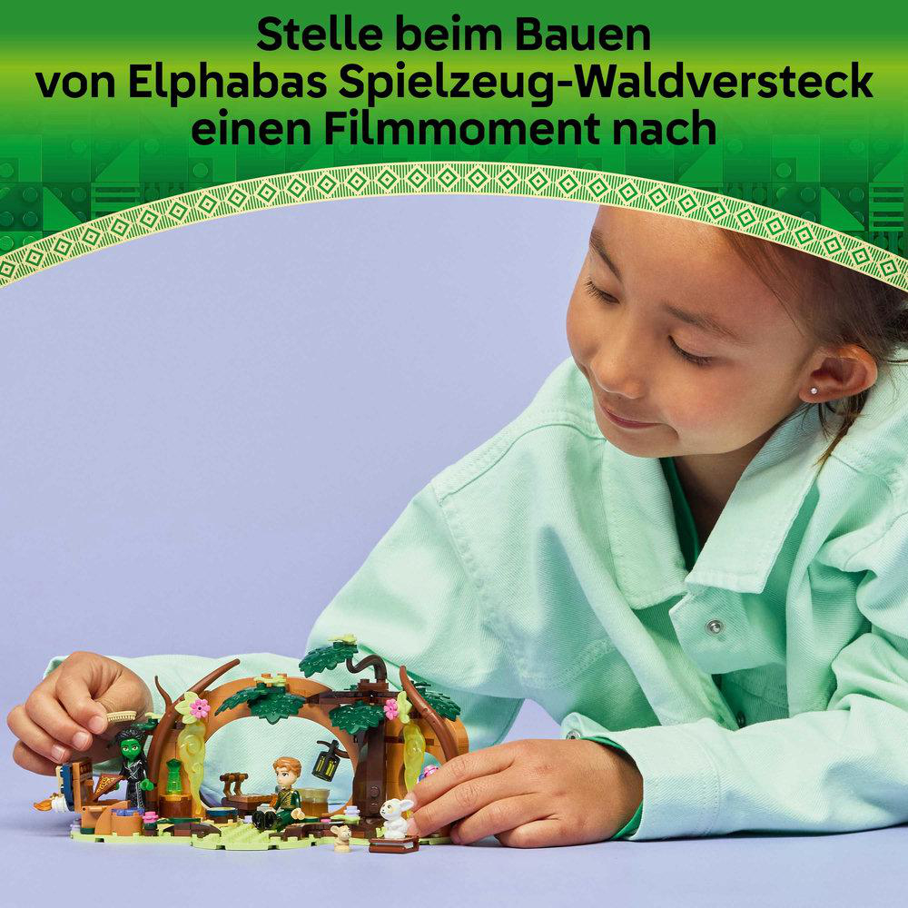 Ein Mädchen betrachtet eine Spielzeug-Waldszene. Die Szene umfasst Figuren, eine Laterne und ein weißes Kaninchen. Oben steht: 'Einen Filmmoment bauen'.