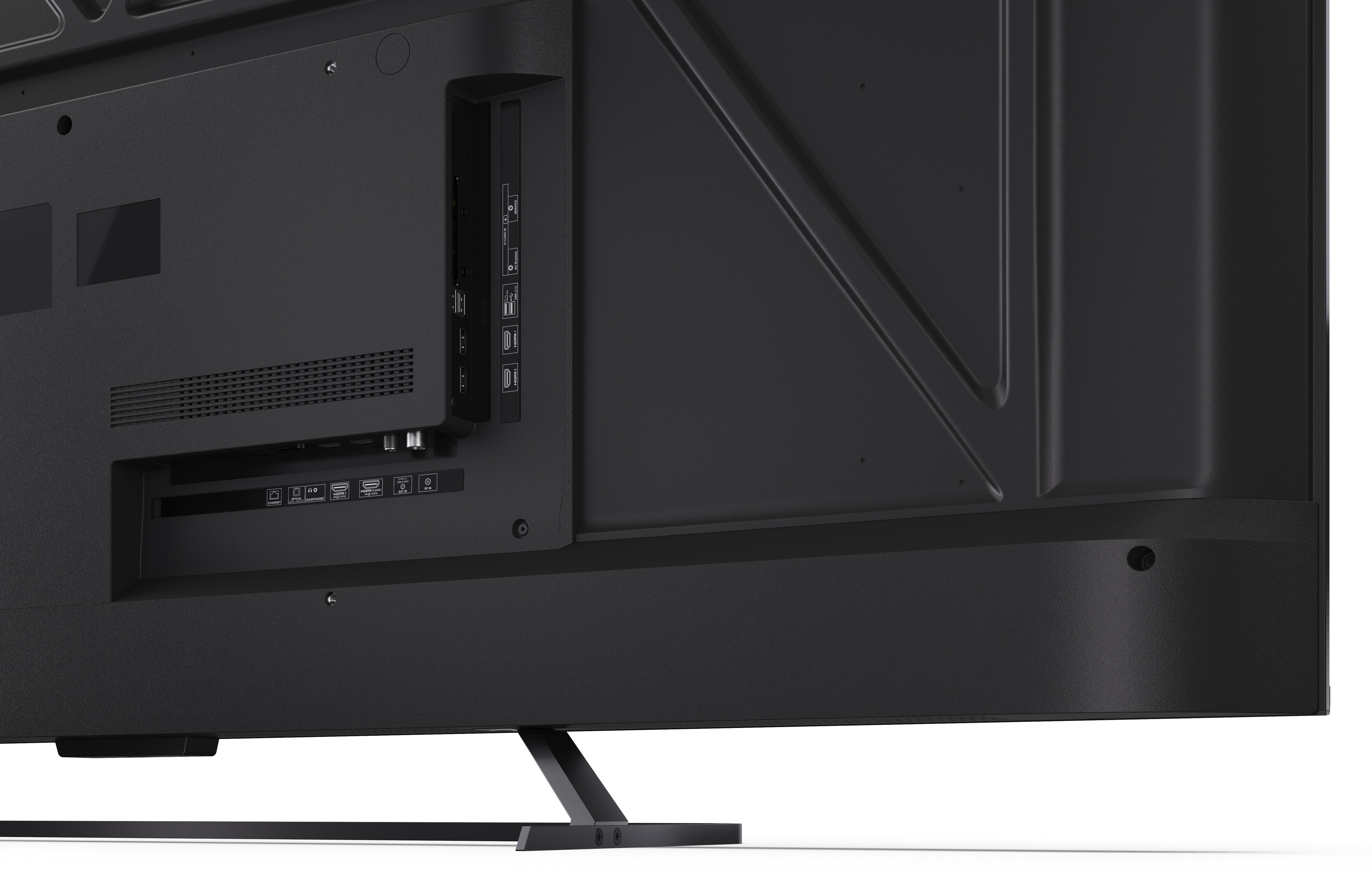 Tył czarnego telewizora. Widoczne porty, podstawka i otwory wentylacyjne. Powierzchnia jest teksturowana i kątowa.
