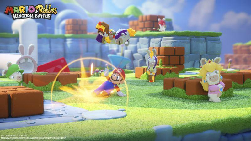 Mario und Rabbids-Charaktere in einer farbenfrohen Kampfszene. Mario greift an, während Rabbids-Charaktere in Aktion sind. Grünes Gras und blauer Himmel.