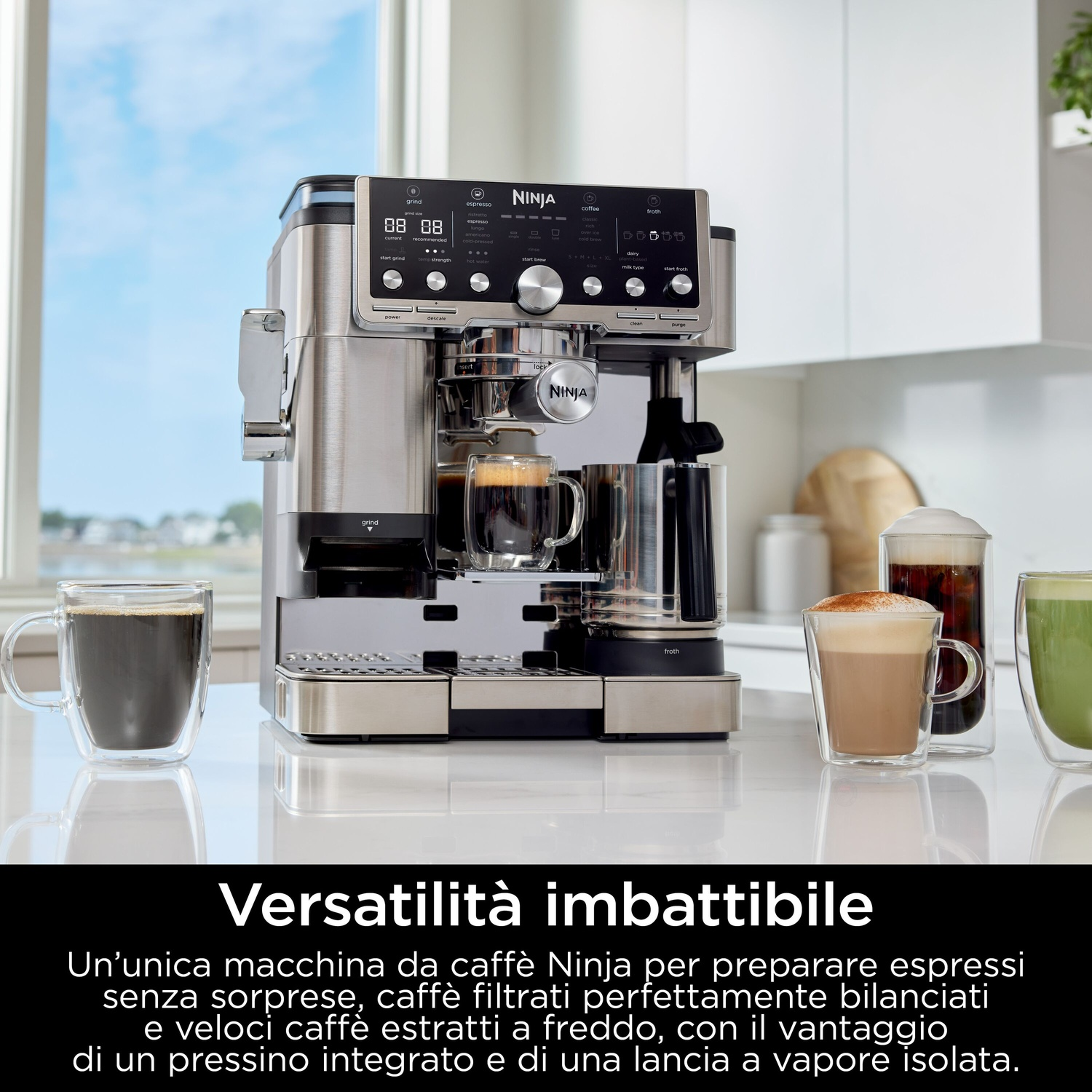 Una macchina da caffè Ninja argentata con caffè in tazze trasparenti. Schiuma e altre bevande al caffè sono anche sul bancone.