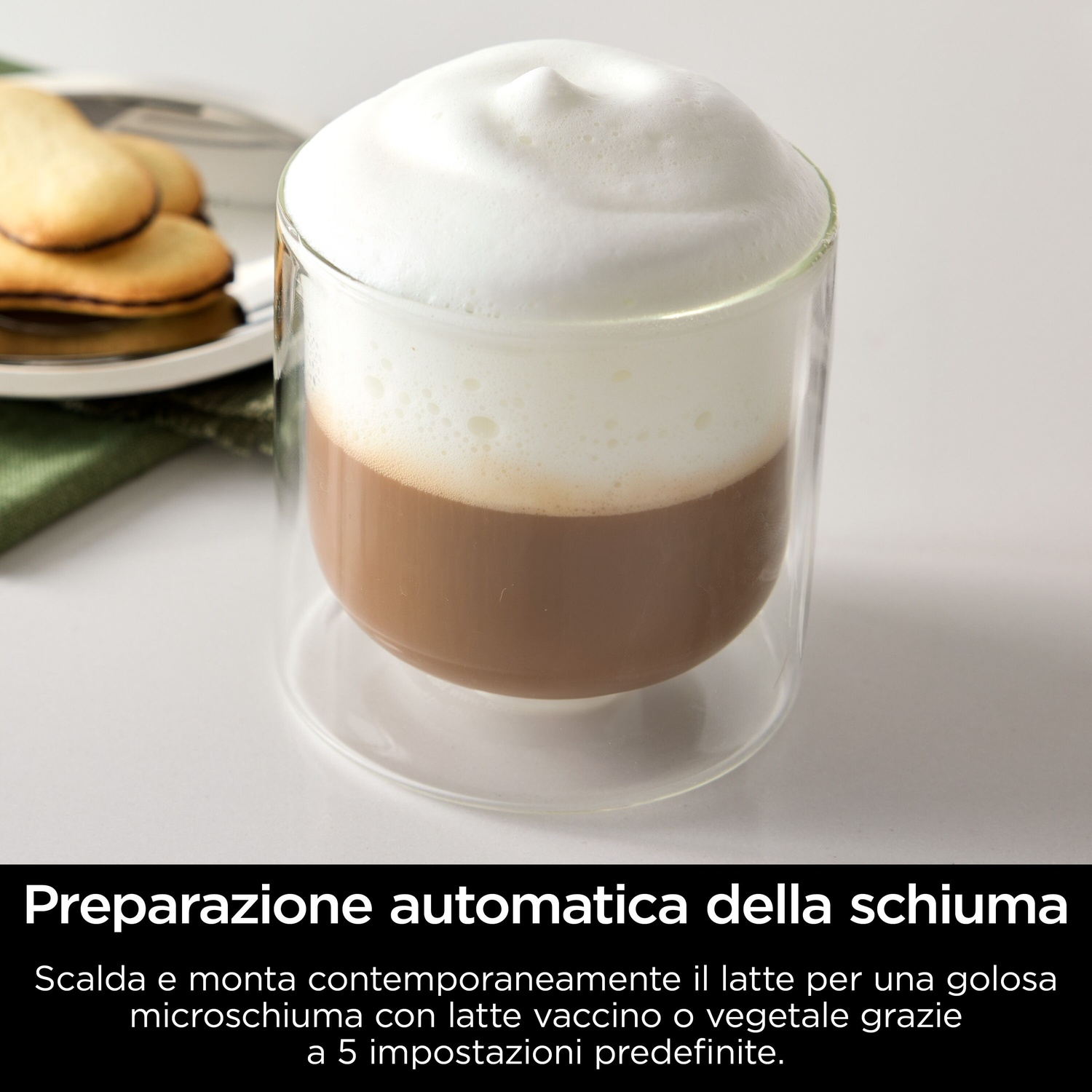 Un bicchiere di caffè con uno spesso strato di schiuma. Biscotti su un piatto sullo sfondo.