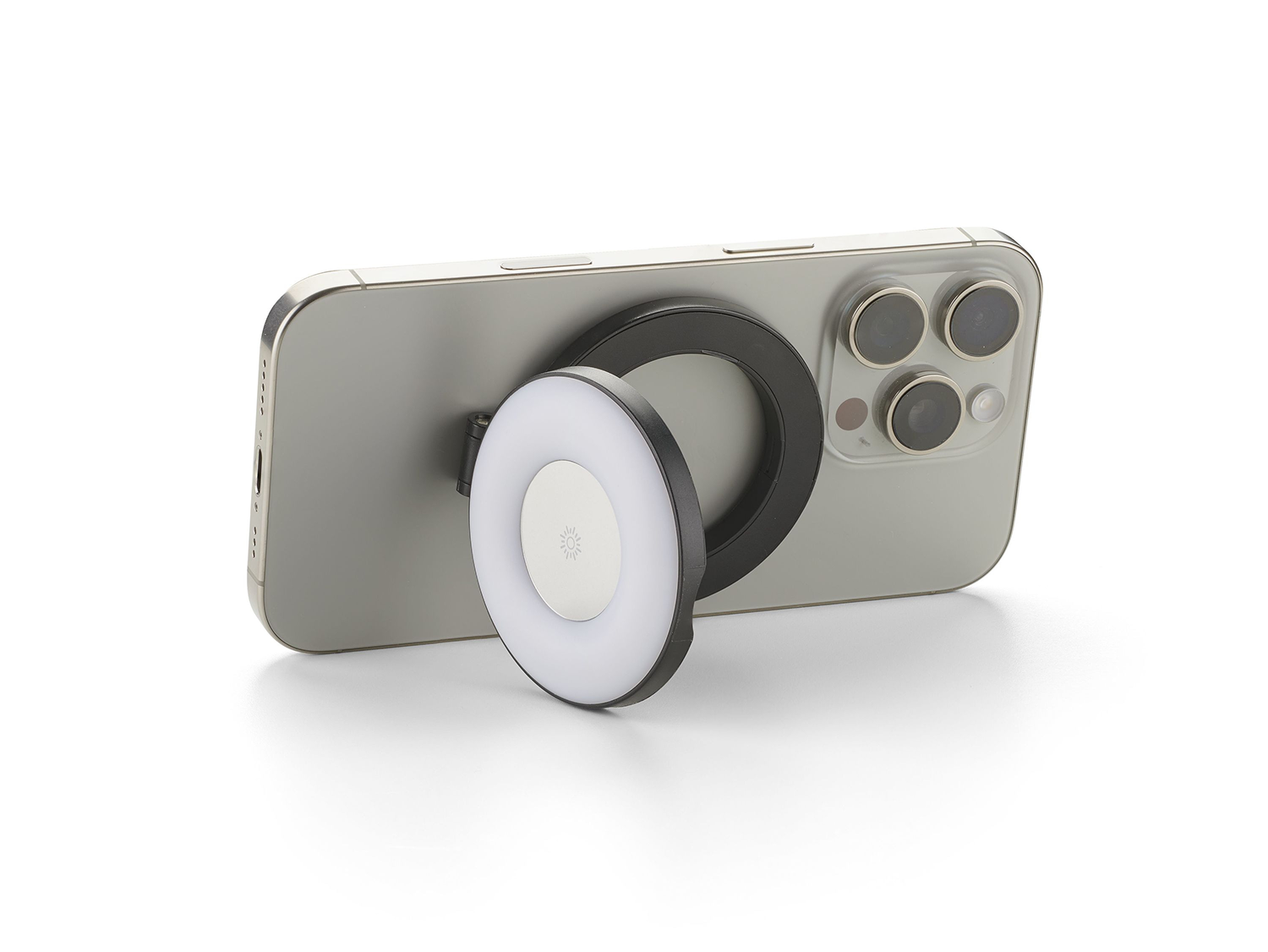 Un iPhone plateado con una luz de anillo negra adjunta. La luz del anillo es blanca y emite luz, con un logotipo de sol.