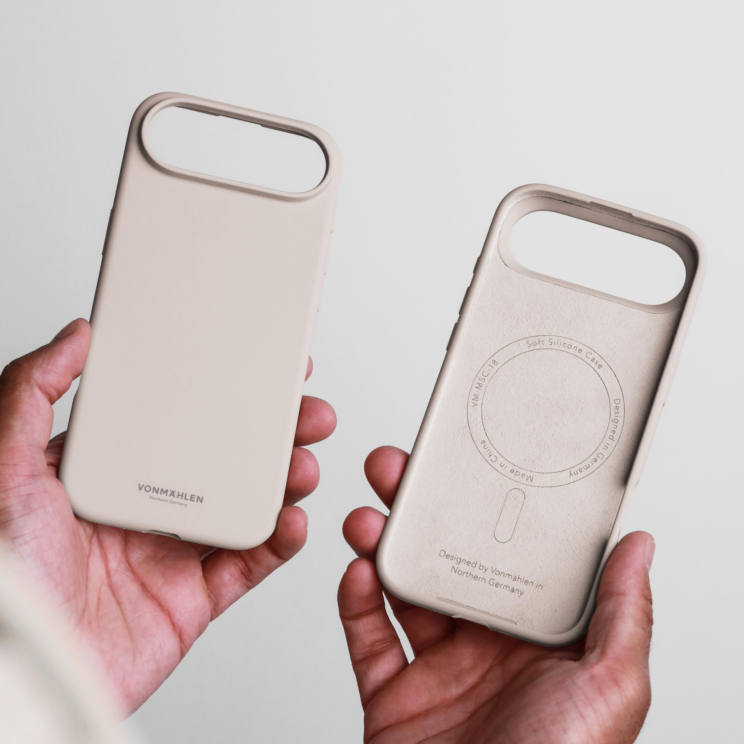 Hände halten zwei Telefonhüllen. Eine zeigt die Innenseite mit Text. Beige Farbe, weiches Silikon. Weißer Hintergrund.