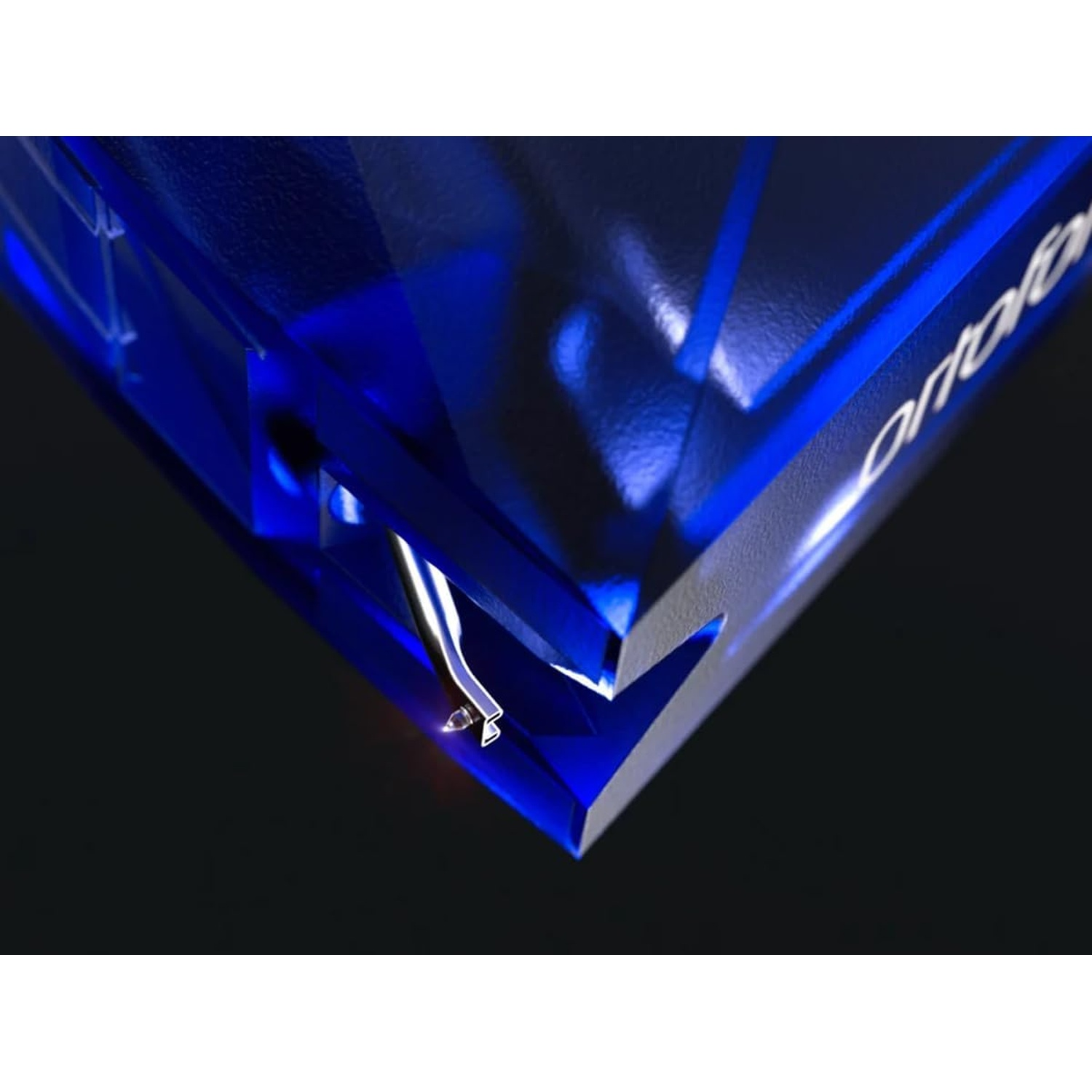 Primo piano di un oggetto blu angolare con un ago argentato. L'oggetto ha un testo bianco e si trova su uno sfondo nero.