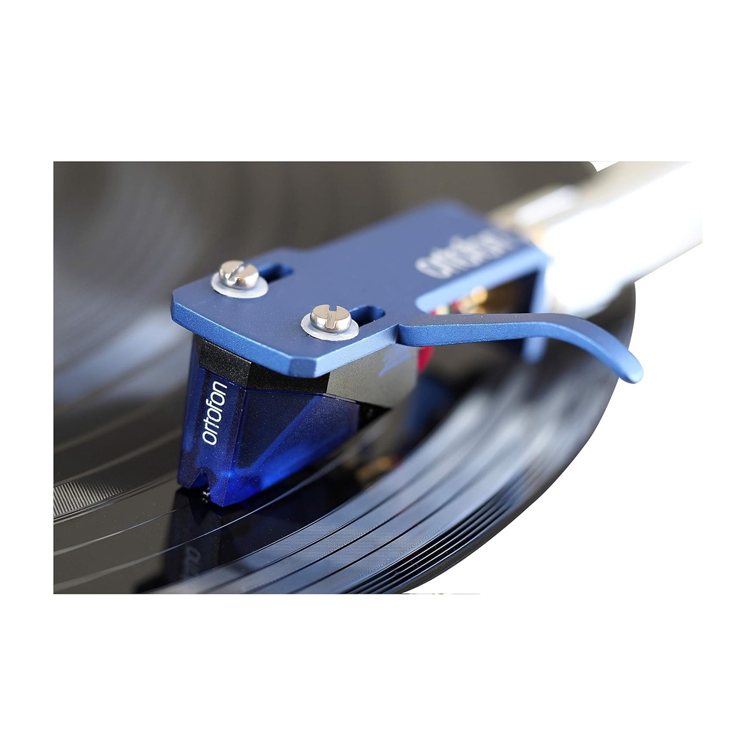 Uno stilo Ortofon blu su un disco in vinile nero. Lo stilo è montato su un braccio blu, con viti. Il disco ha dei solchi.