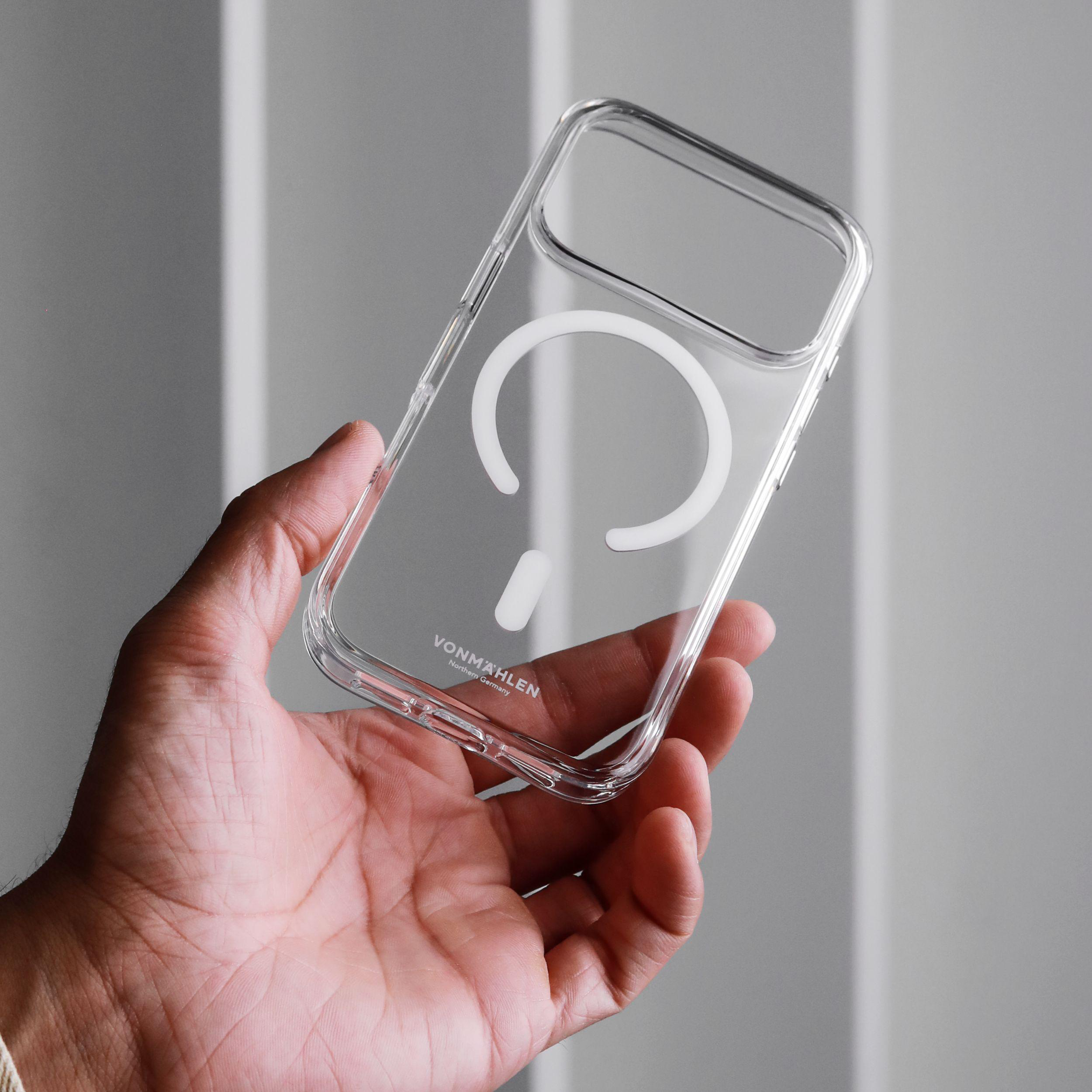 Eine Hand hält eine durchsichtige Handyhülle mit weißem MagSafe-Design. Der Hintergrund ist hellgrau.