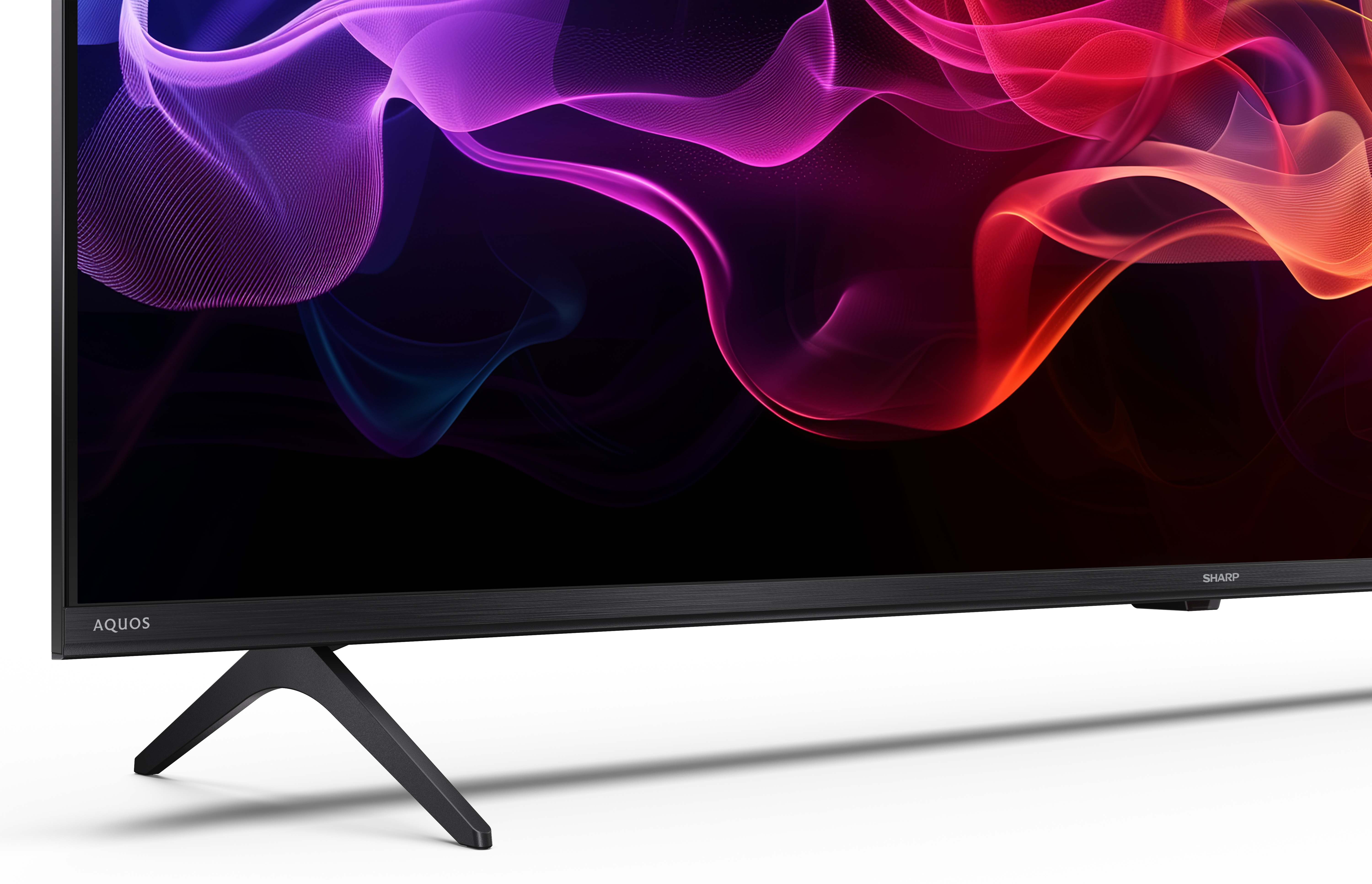 Telewizor Sharp Aquos z kolorowym, płynącym, abstrakcyjnym wyświetlaczem. Czarny stojak i ramka. Białe tło.