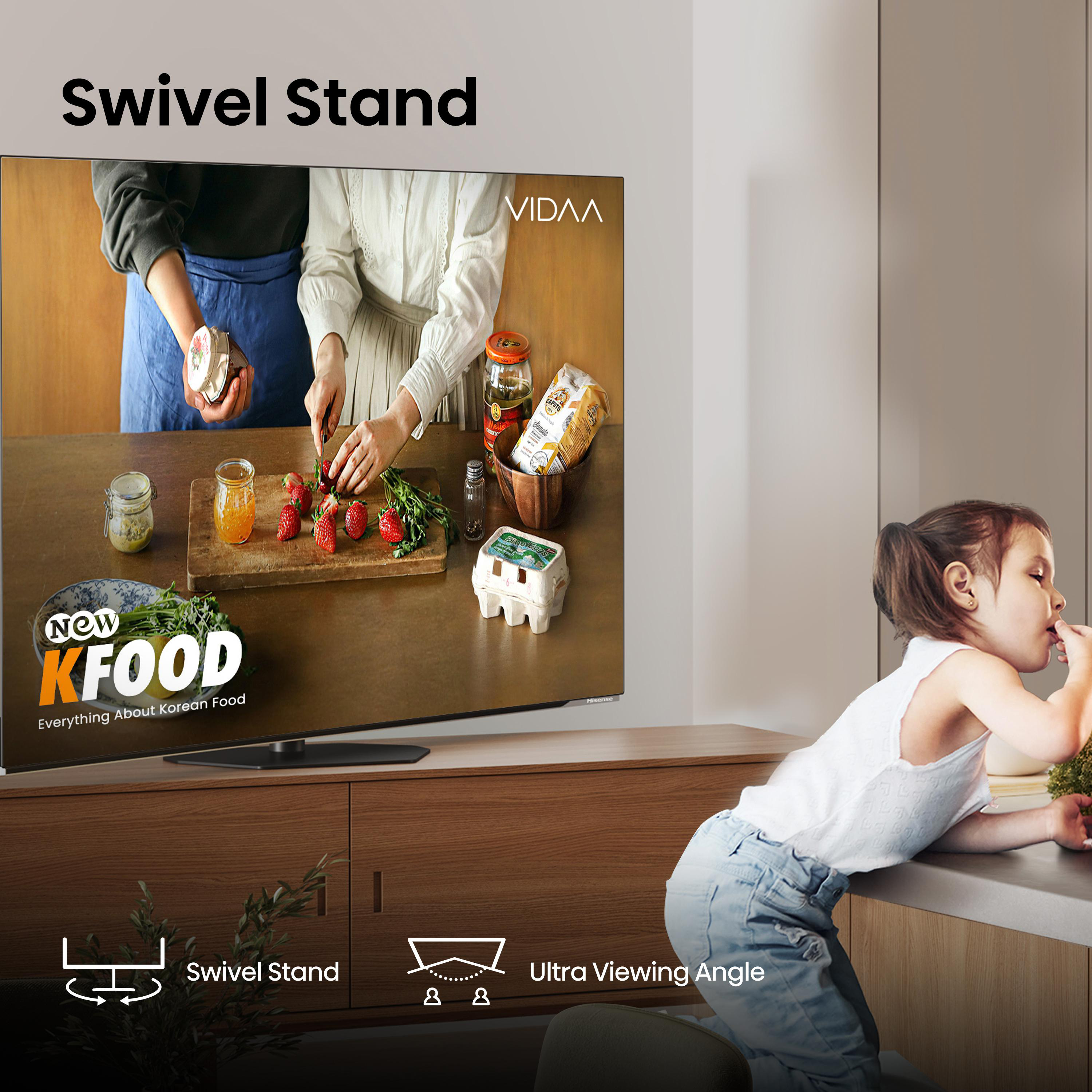 Ein Fernseher zeigt eine Kochszene. Ein Mädchen isst Gemüse. Text sagt 'Swivel Stand' und 'Ultra Viewing Angle'.