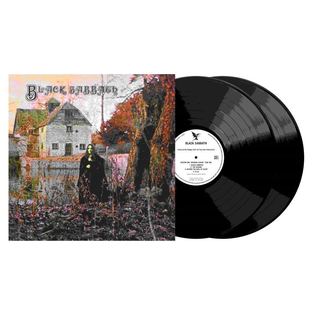 Ein Mann in Schwarz vor einem Haus, neben Schallplatten.