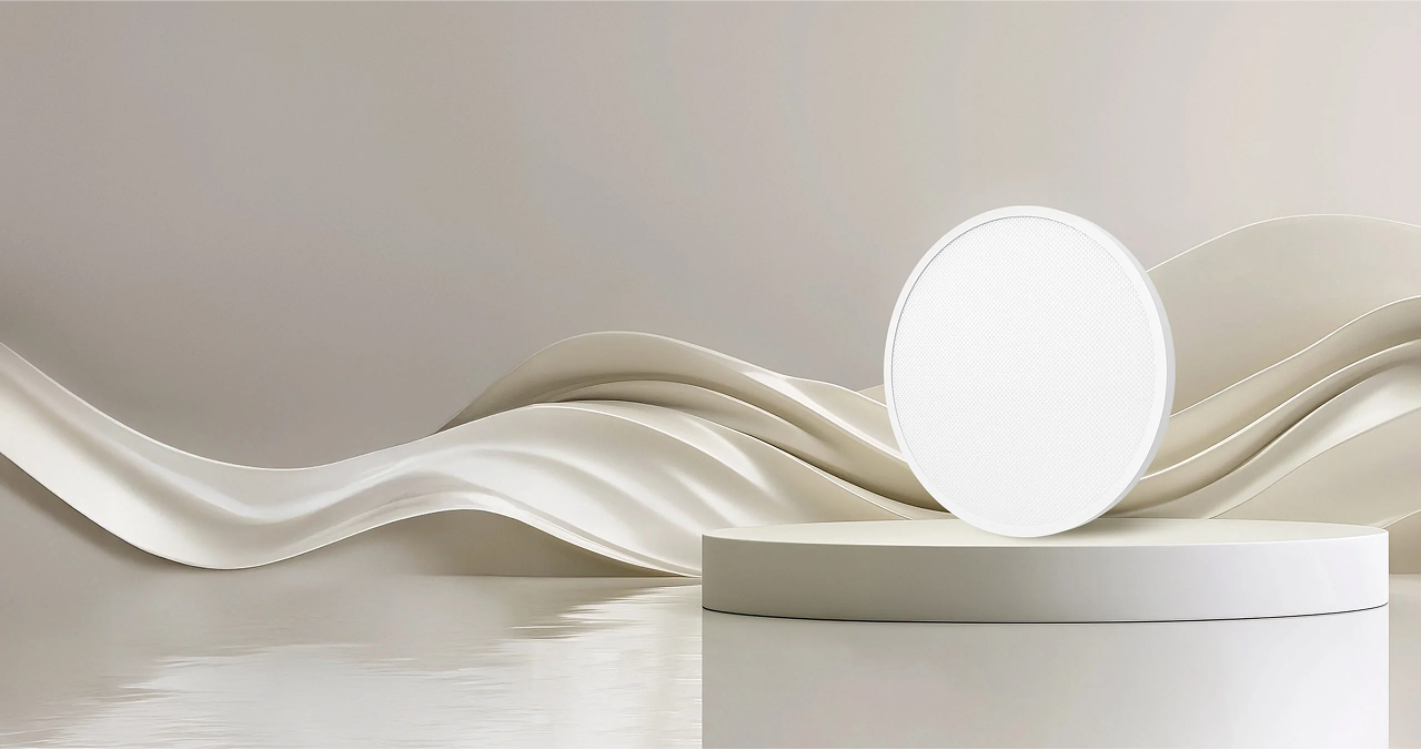 Biały okrągły głośnik na białym podium. Beżowe faliste tło z odblaskową powierzchnią.