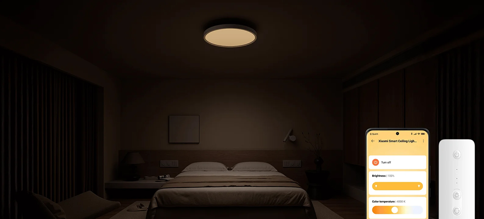 Słabo oświetlona sypialnia z inteligentną lampą sufitową. Telefon wyświetla sterowanie oświetleniem obok pilota.