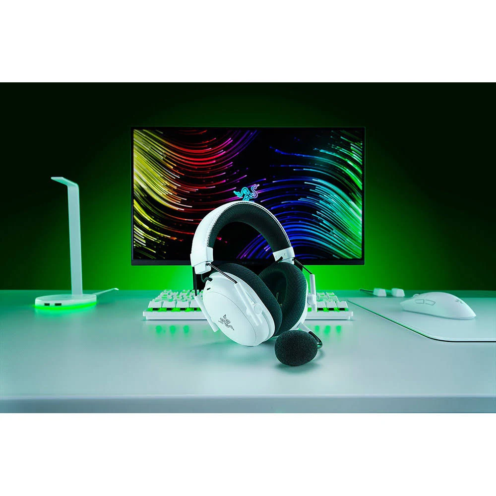Auriculares gaming blancos con micrófono, teclado, ratón y monitor. El fondo es verde.