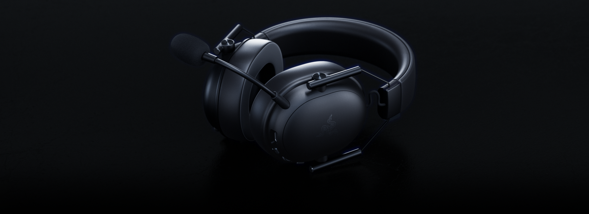 Auriculares gaming negros con micrófono sobre superficie negra. El logo de Razer es visible en la copa.
