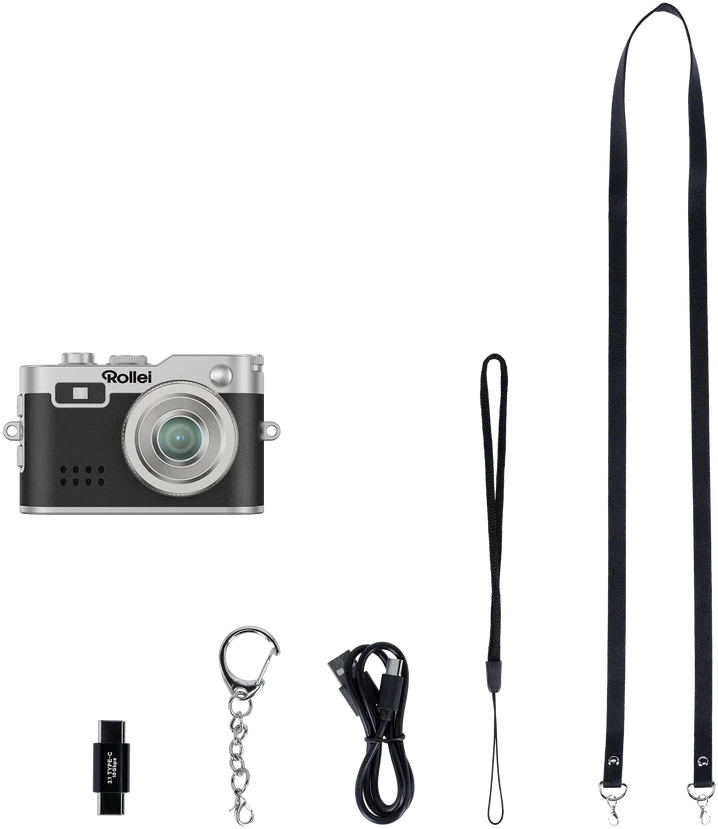 Eine Kamera mit Zubehör: ein Gurt, eine Handschlaufe, ein USB-Kabel und ein Schlüsselanhänger mit USB-C-Laufwerk. Alles auf schwarzem Hintergrund.