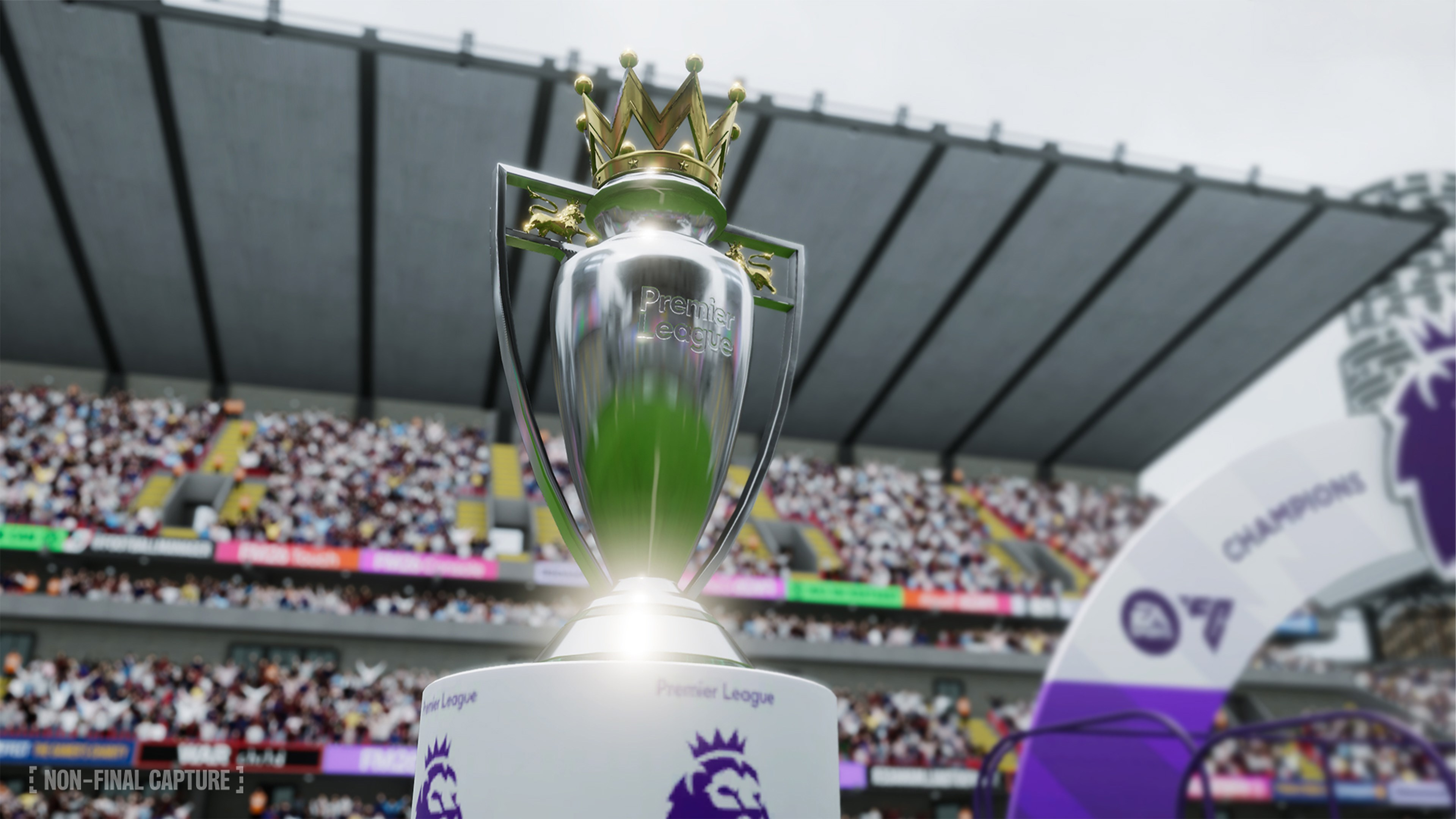 Die Premier-League-Trophäe mit goldener Krone in einem Stadion mit Fans im Hintergrund. Champions-Schild rechts.