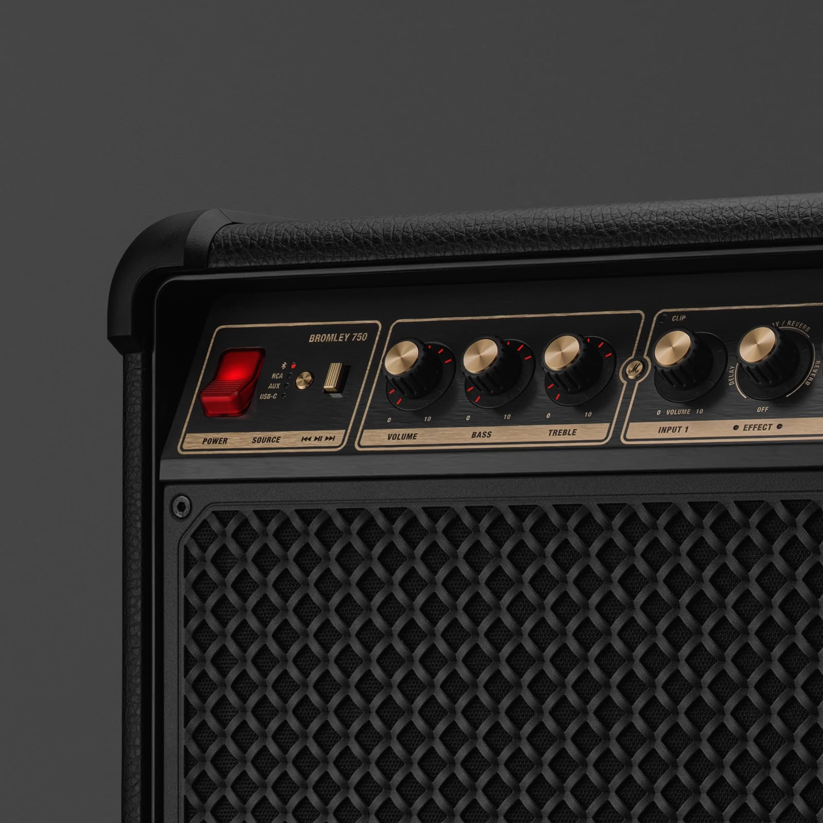 Gros plan sur un amplificateur noir et or. Il comporte des boutons, un interrupteur d'alimentation et une grille de haut-parleur.