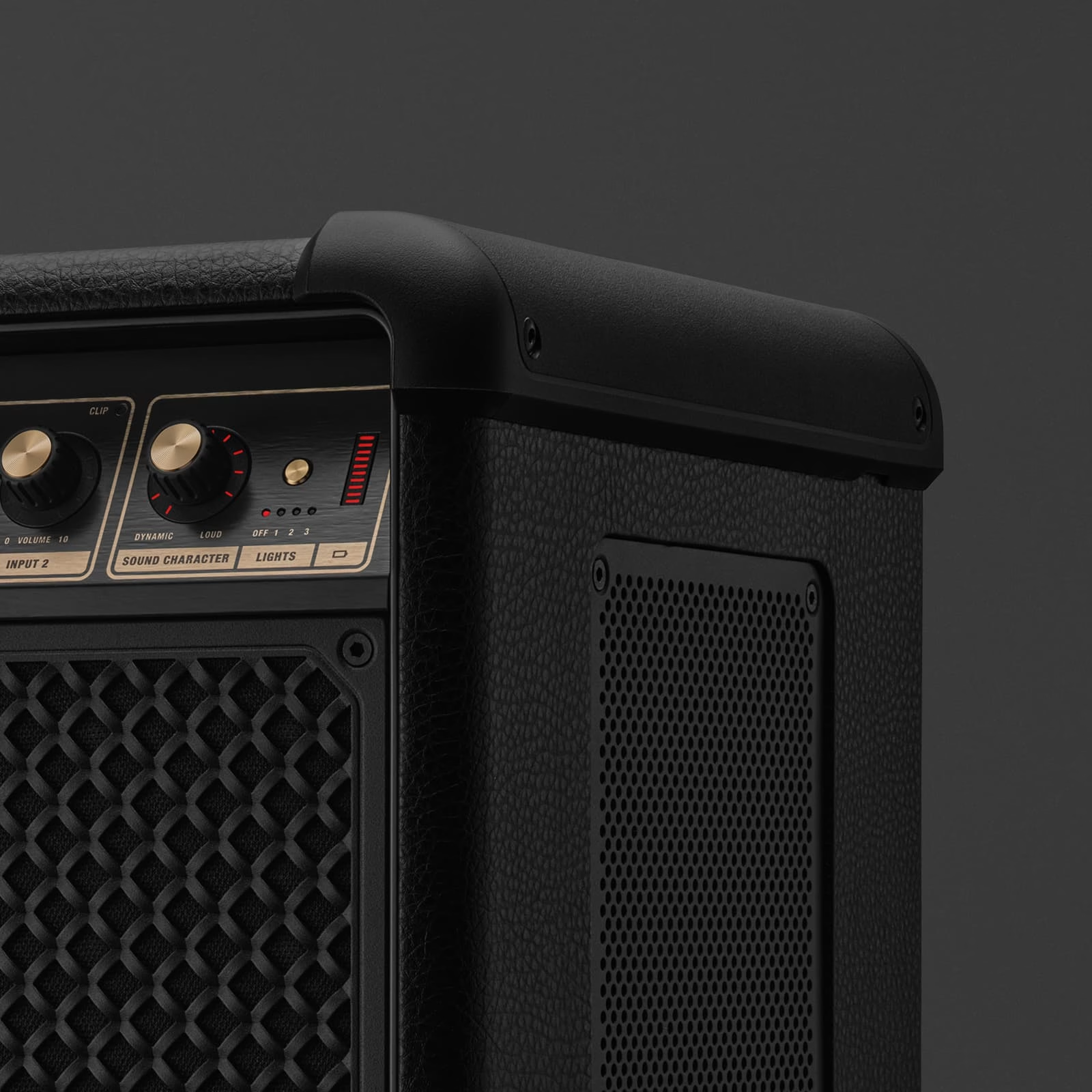 Gros plan sur un amplificateur de guitare noir. On voit des boutons, des lumières et une grille de haut-parleur. Le fond est gris foncé.