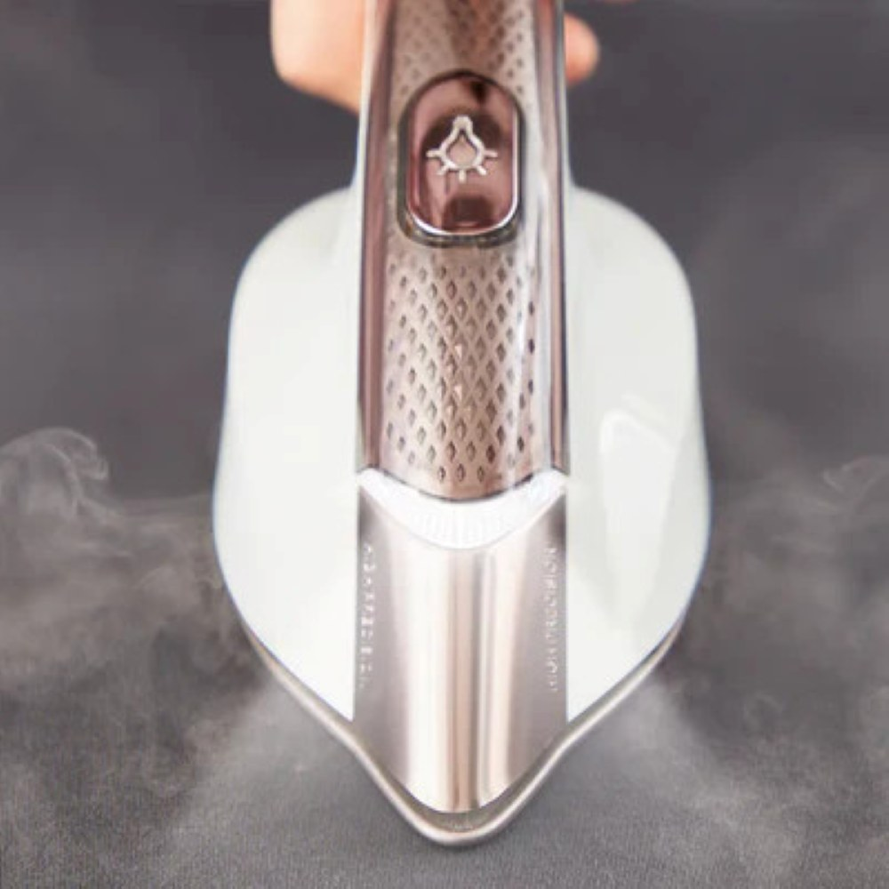 Biała i metalowa parownica ręczna paruje ciemnoszarą tkaninę. Para jest widoczna. Urządzenie ma przycisk i etykietę 'HIGH PRECISION'.