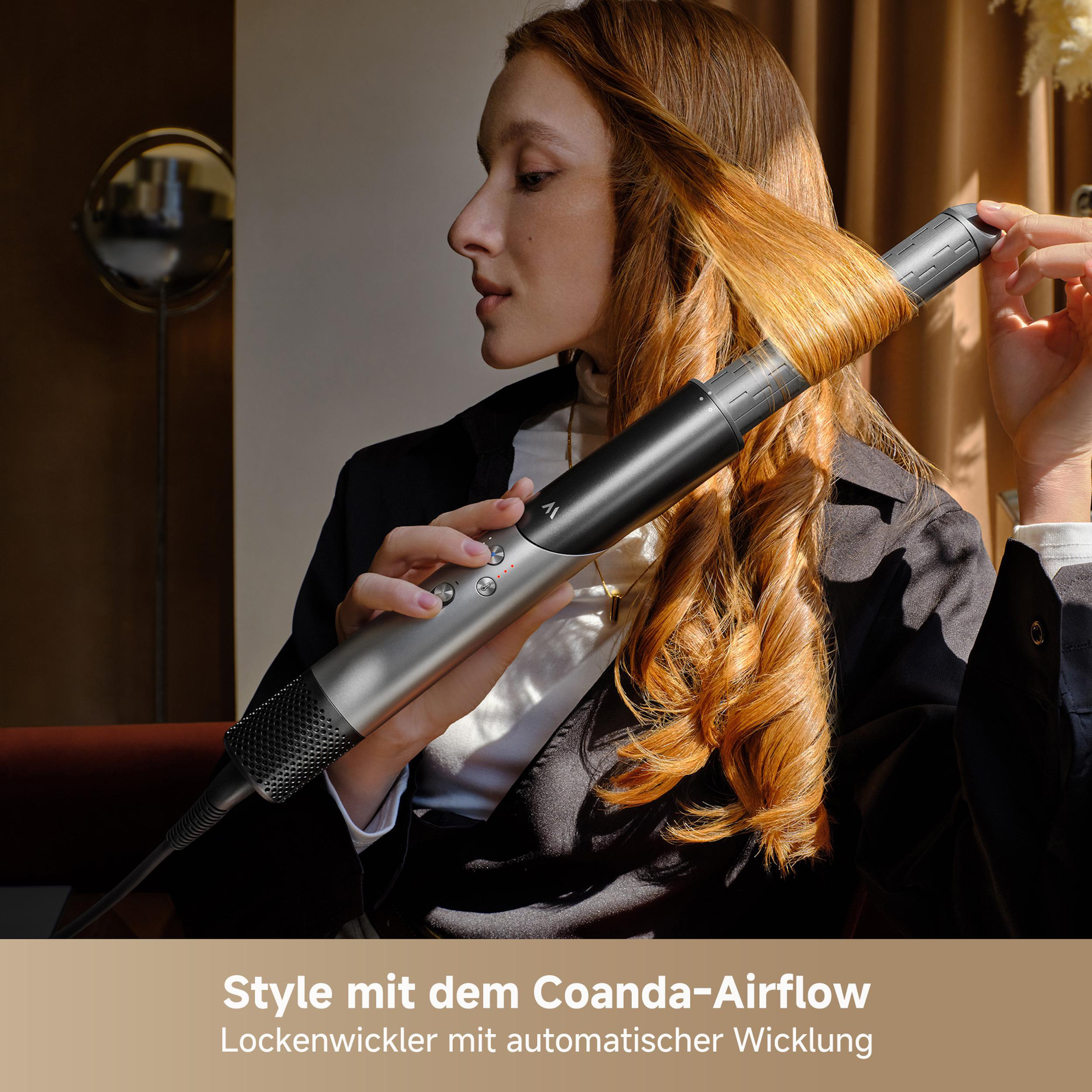 Eine Frau mit roten Haaren benutzt einen Lockenstab. Der Lockenstab ist grau und schwarz.