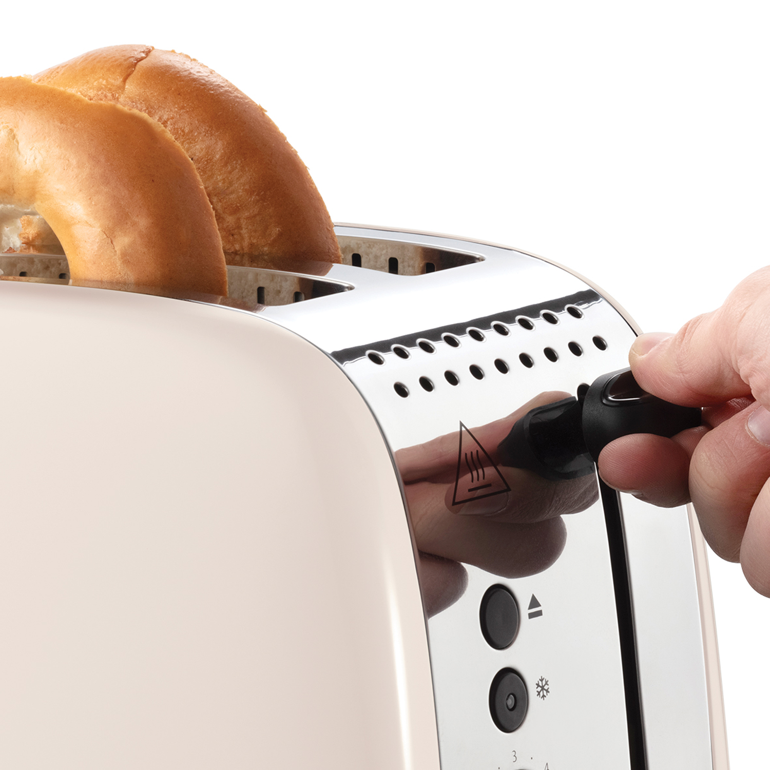 A toaster with two bagels inside. A hand is adjusting the power setting. The toaster is beige with chrome accents.